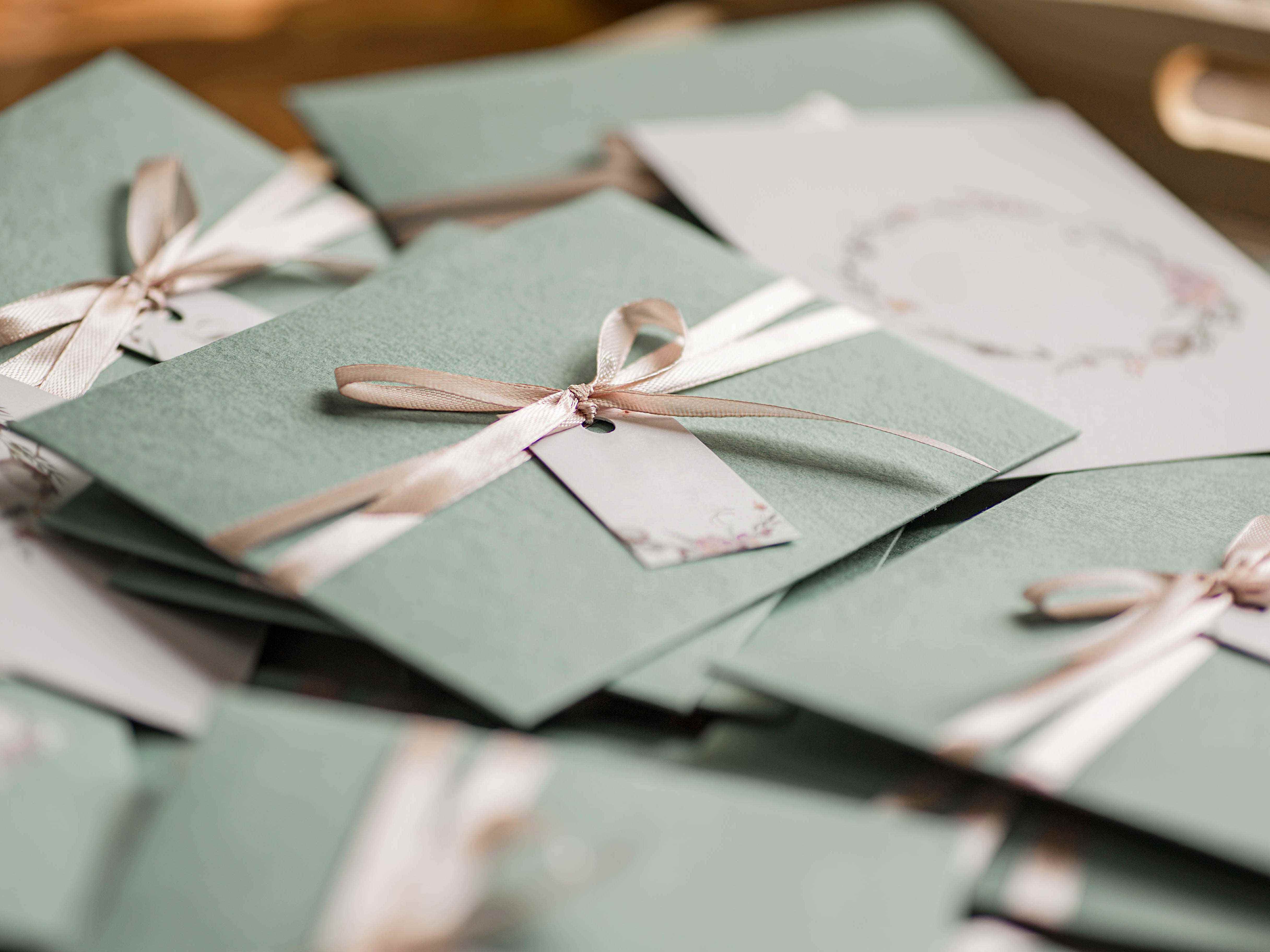 ein Haufen grüner Umschläge mit Bändern darauf, Hochzeitseinladungen