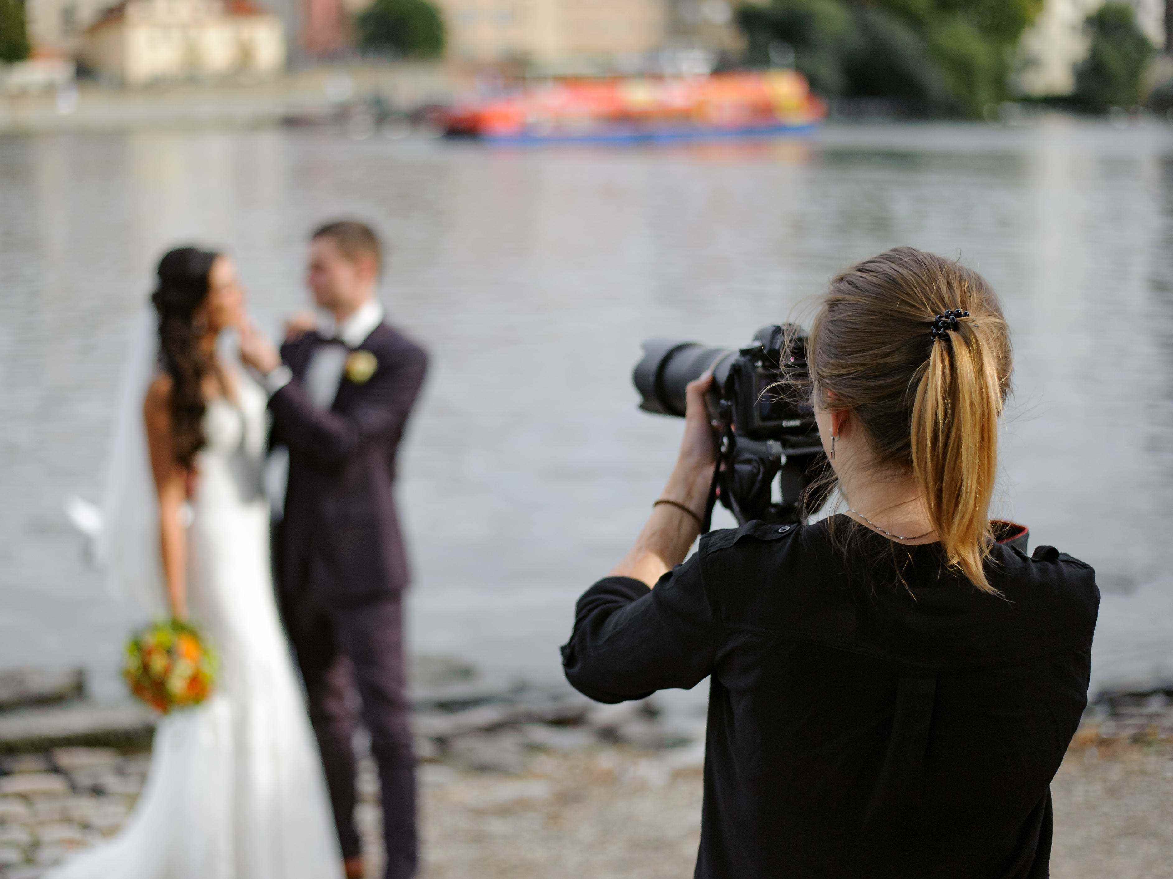 Fotograf fotografiert Braut und Bräutigam auf dem Wasser