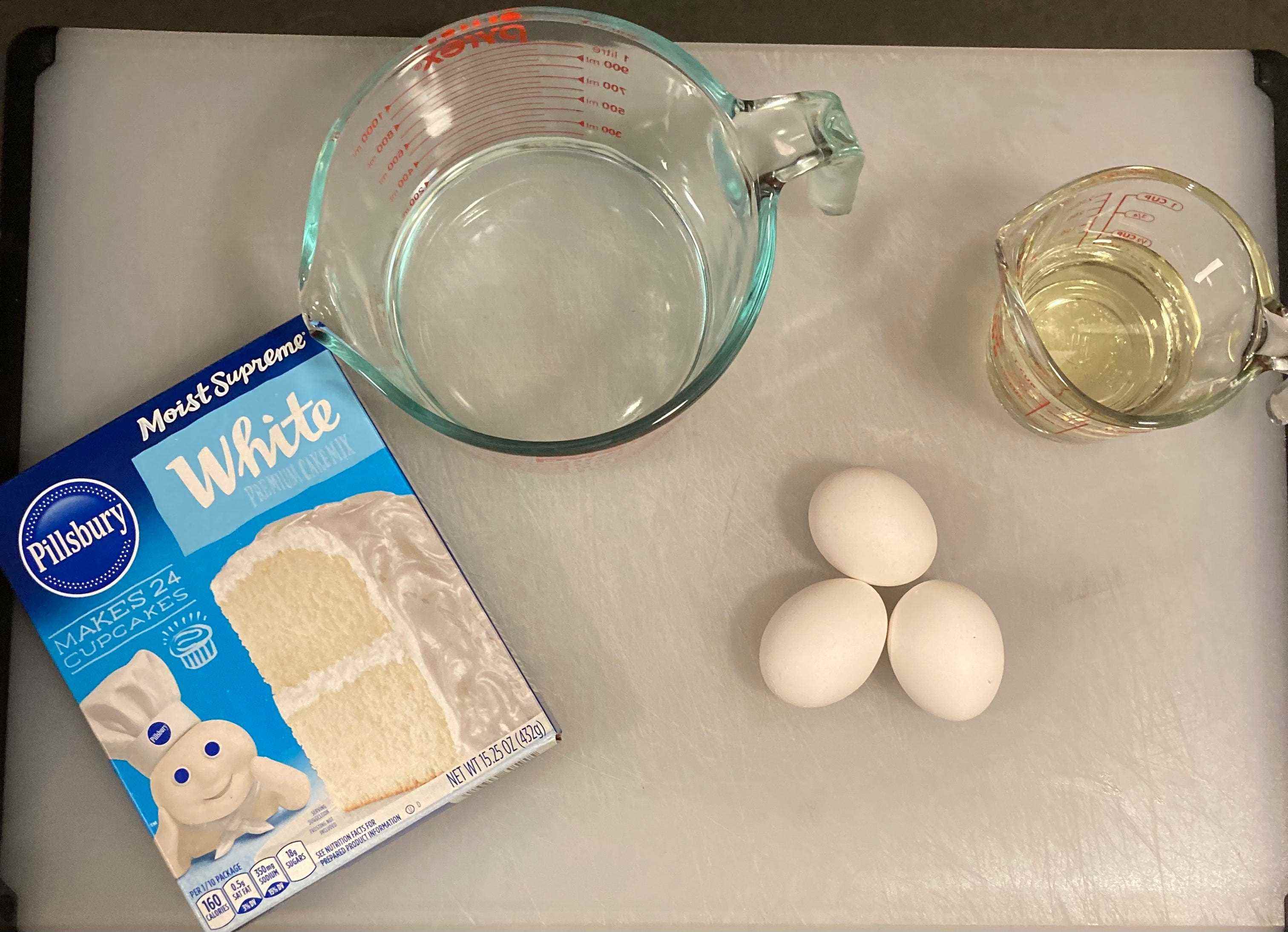 Eine Pillsbury-Kuchenmischung auf einem weißen Tablett mit Messbechern mit Öl und Wasser und Eiern