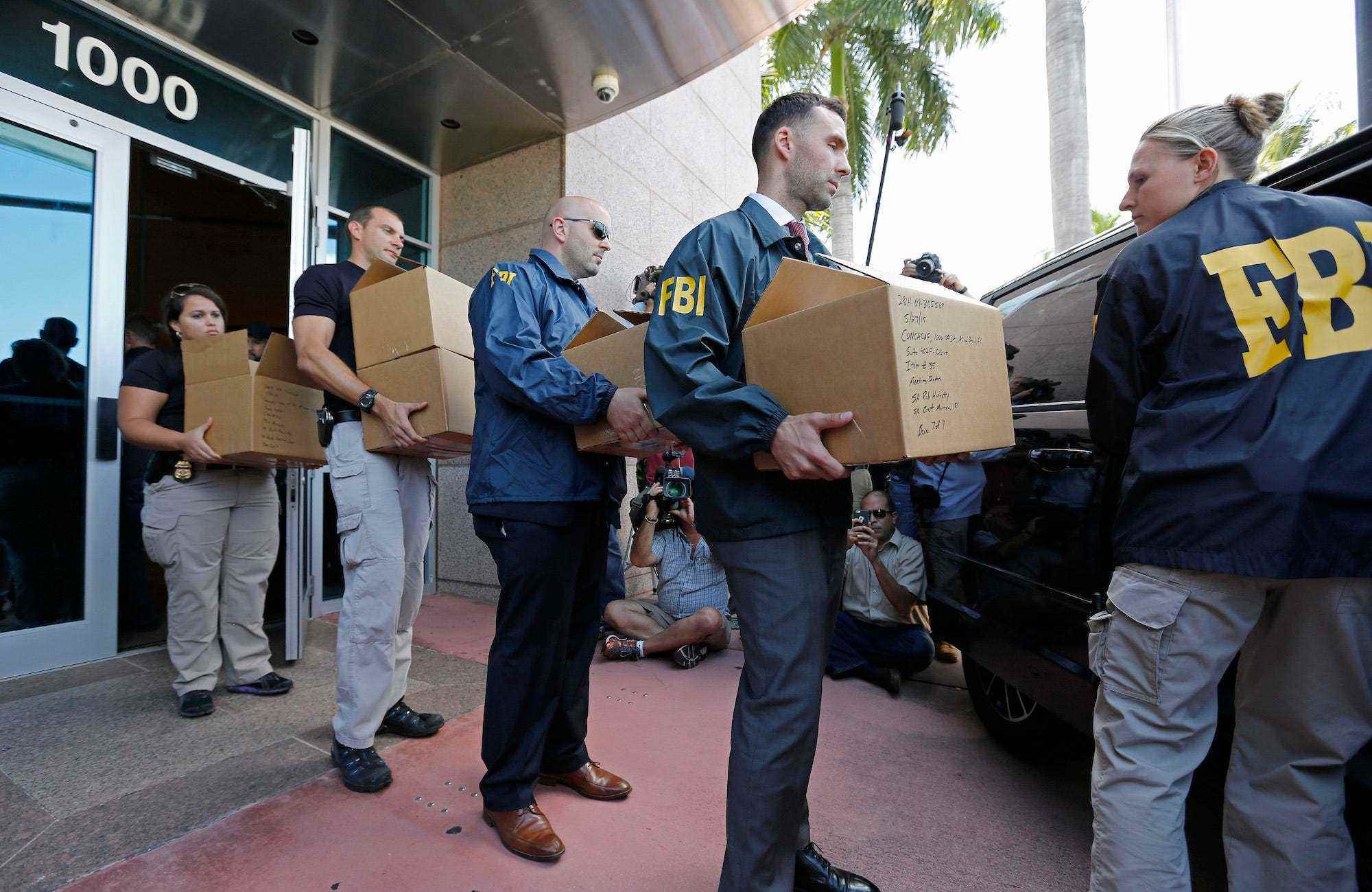 FBI-Agenten tragen Kisten aus dem Hauptquartier von CONCACAF, nachdem es am 27. Mai 2015 in Miami Beach, Florida, durchsucht wurde.  Die Razzia ist Teil einer internationalen Untersuchung der FIFA, bei der neun FIFA-Beamte und fünf Führungskräfte des Unternehmens wegen Erpressung, Drahtbetrug und Verschwörung der Geldwäsche angeklagt wurden