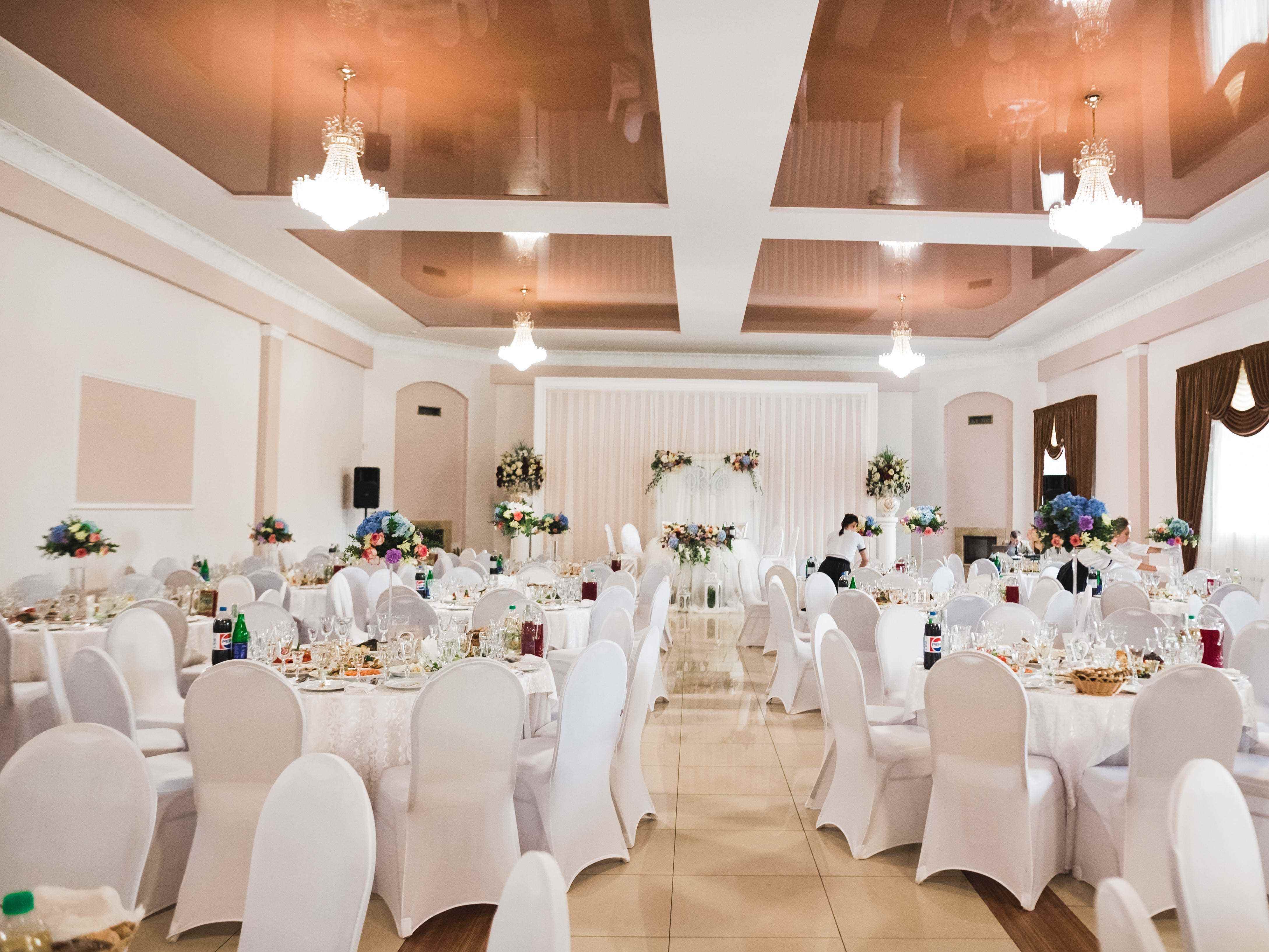 ein Bankettsaal für Hochzeiten mit weißen Stühlen und Tischen