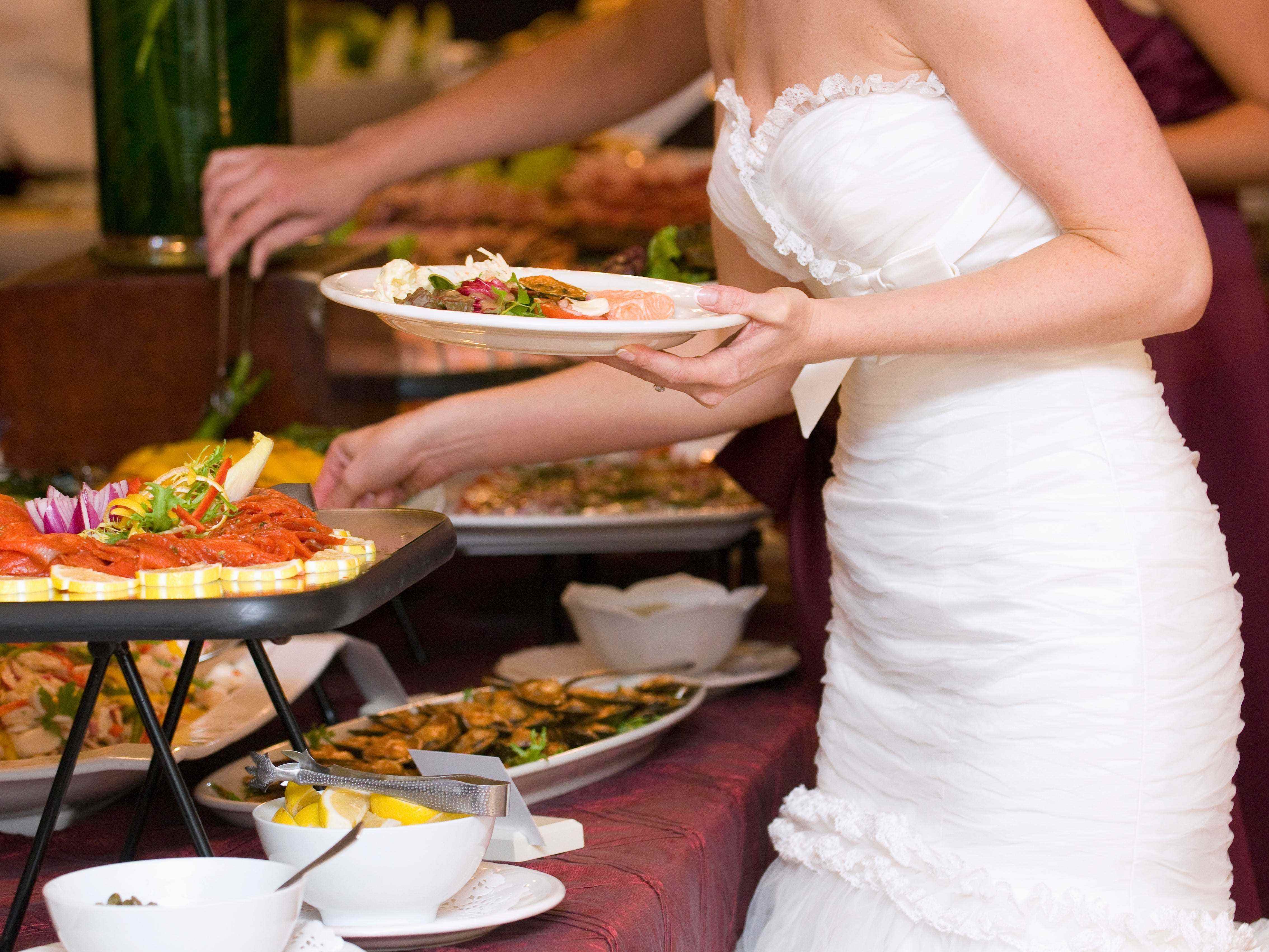 Braut im weißen Kleid, das sich bei ihrer Hochzeit etwas zu essen serviert