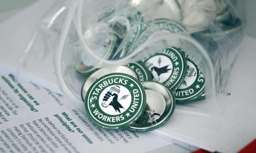 Anstecknadeln sagen „Starbucks Workers United“ in einem grünen Kreis, wie das Firmenlogo, aber mit einer Hand in der Mitte, die eine Flasche hält