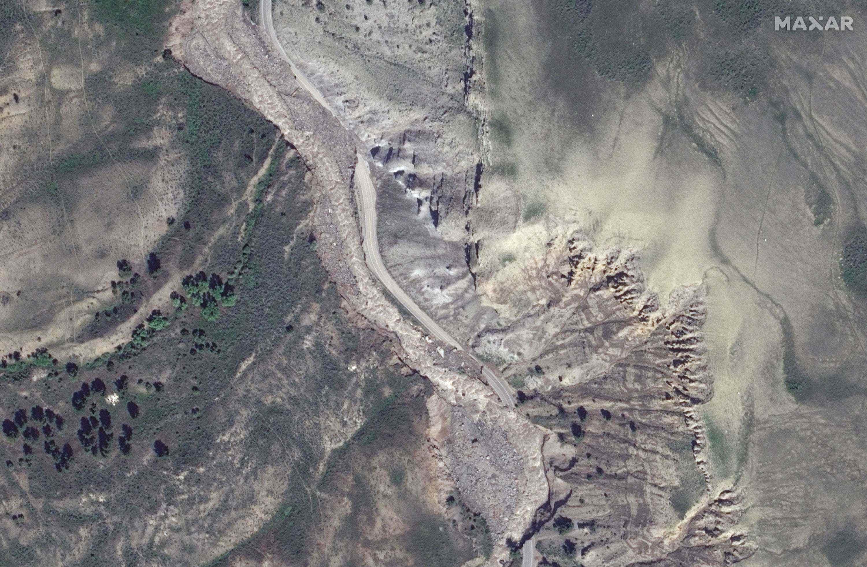 Das Satellitenbild zeigt eine Bergstraße mit großen Abschnitten, die entlang eines graubraunen Flusses weggebröckelt sind