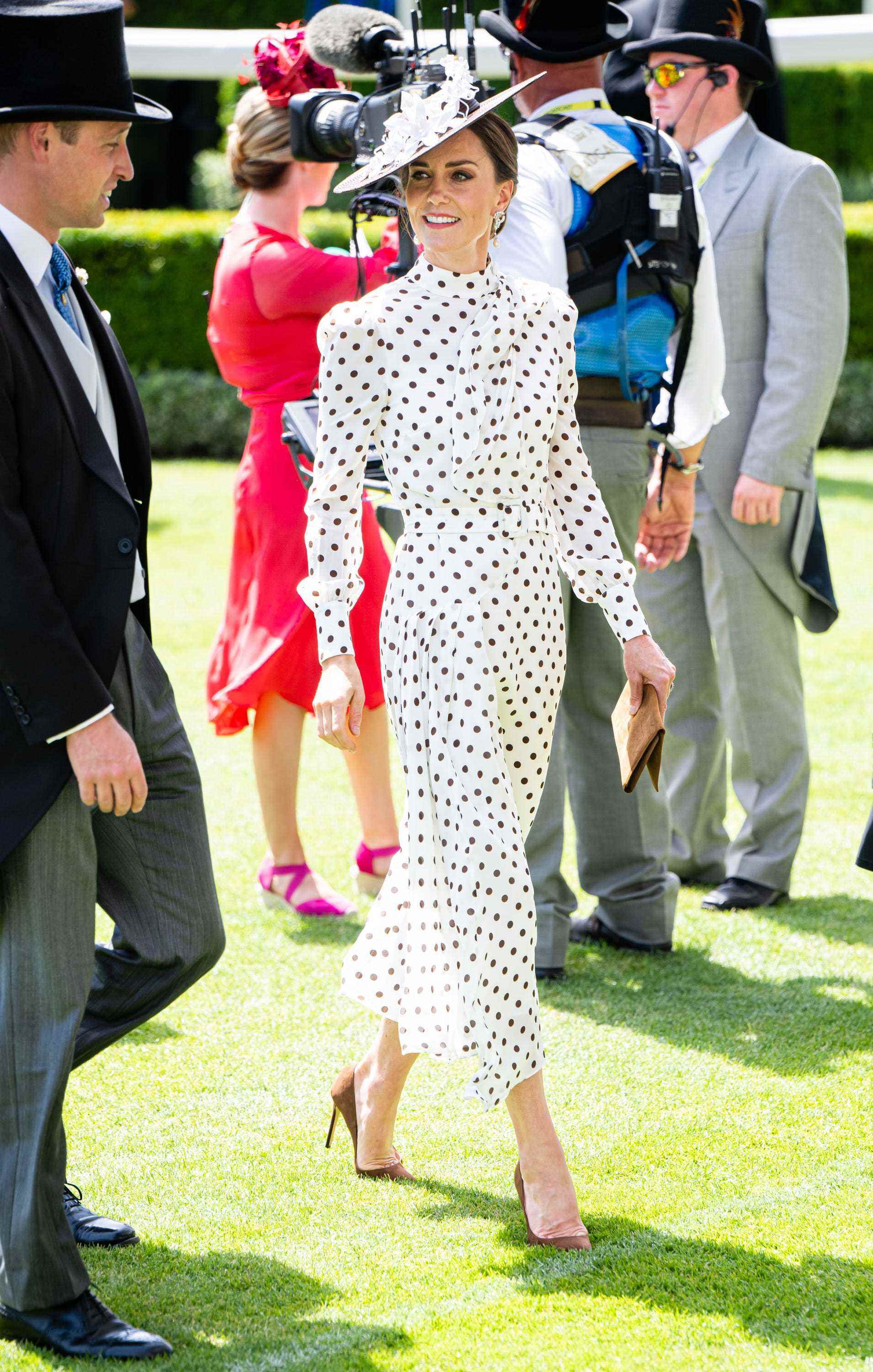 Kate Middleton trägt ein weiß-braunes gepunktetes Kleid und einen braunen Hut