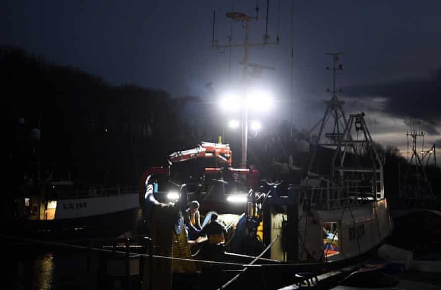 Arbeiter entladen einen Trawler nachts unter Beleuchtung