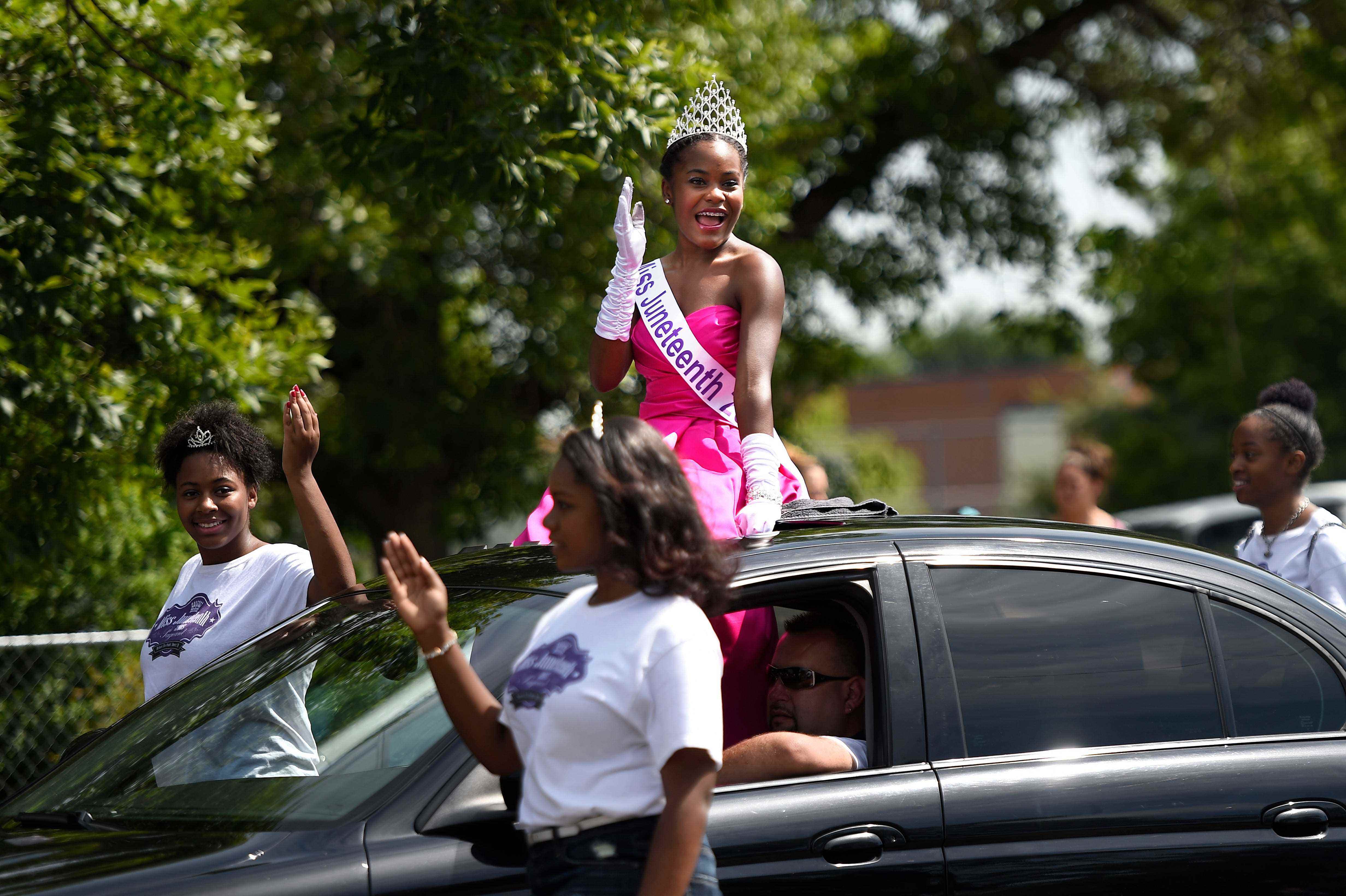 Miss Juneteenth winkt während einer Parade aus einem Auto.