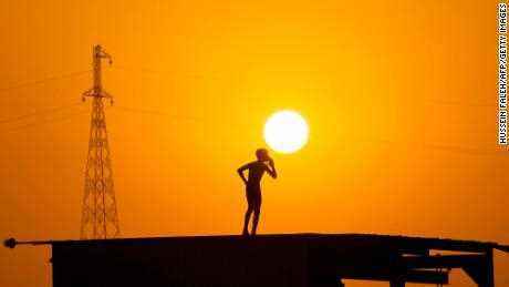 Ein Junge bereitet sich darauf vor, vom Dach eines Gebäudes zu springen, um sich in den Gewässern der Wasserstraße Shatt al-Arab abzukühlen, die am Zusammenfluss von Euphrat und Tigris in der südirakischen Stadt Basra bei Sonnenuntergang im Juni entstanden ist 18.
