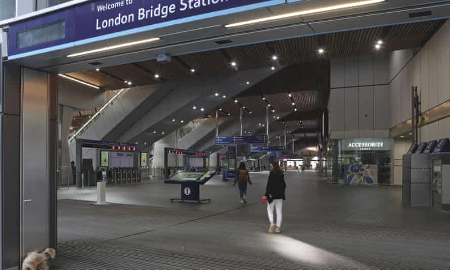 Eine Frau führt ihren Hund in einen fast leeren Bahnhof London Bridge in London.