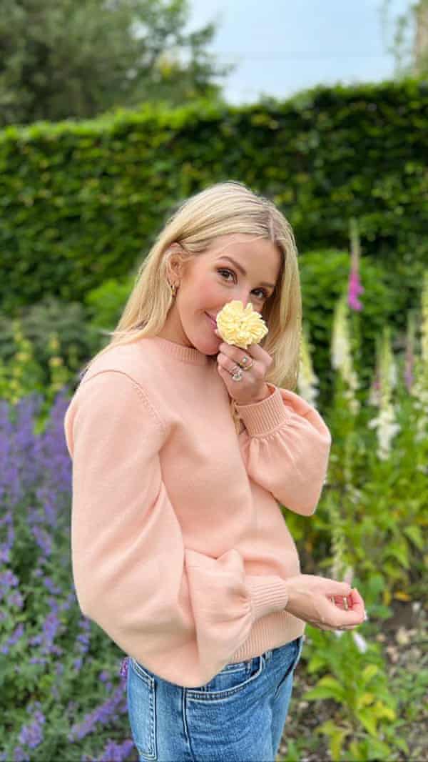 Ellie Goulding steht in einem Garten und hält sich eine Rose vors Gesicht