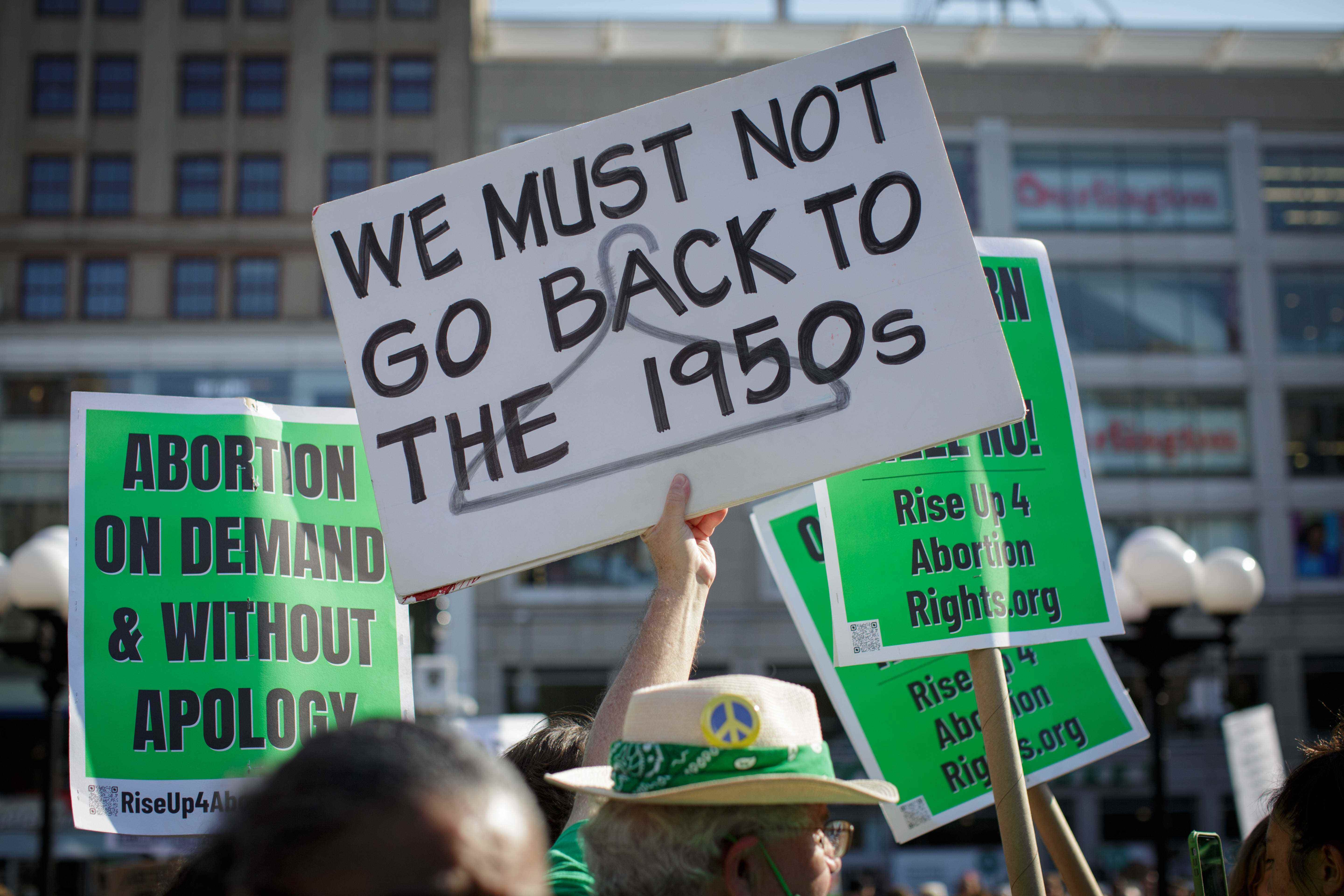 Eine Hand hält ein Schild: „Wir dürfen nicht in die 1950er Jahre zurückgehen“