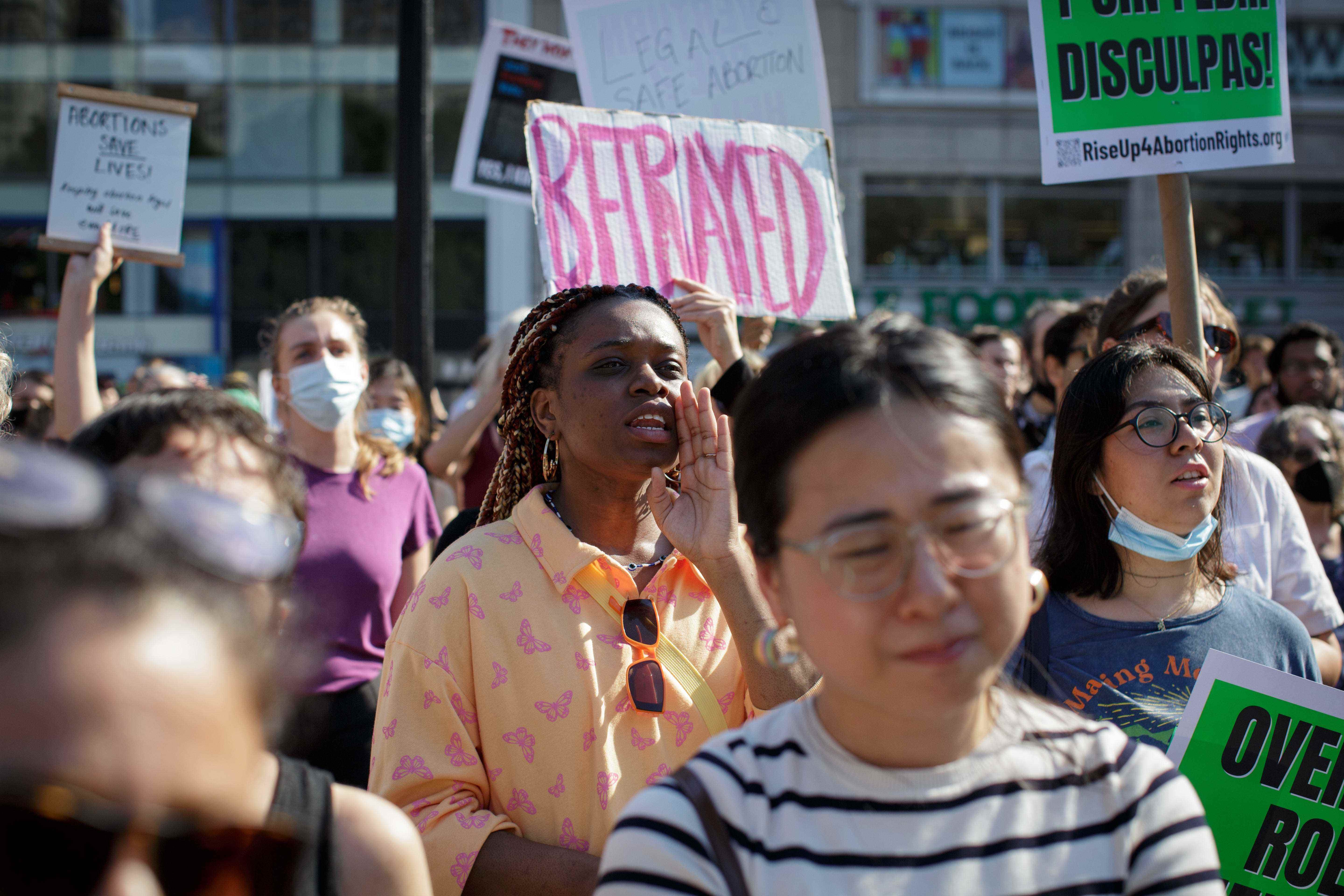 „Betrayed“ steht in rosa Buchstaben auf einem Plakat, das bei einem Protest hochgehalten wird.