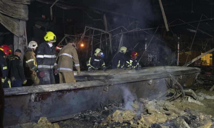Feuerwehrleute des ukrainischen staatlichen Rettungsdienstes beseitigen Trümmer eines Einkaufszentrums, das nach einem Raketenangriff in Kremenchuk, Ukraine, am frühen Dienstag abgebrannt war.
