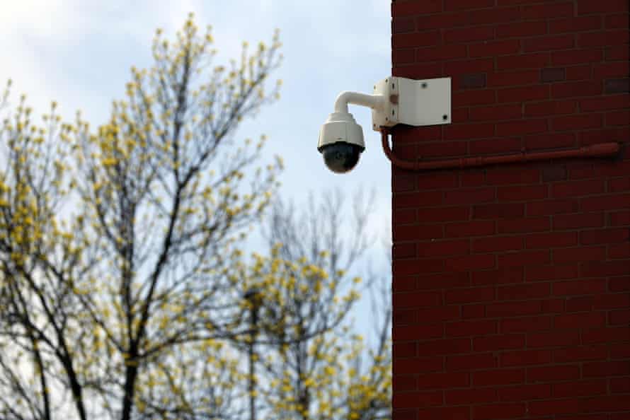 Eine weiße kuppelförmige Kamera ist an der Ecke eines roten Backsteingebäudes montiert.