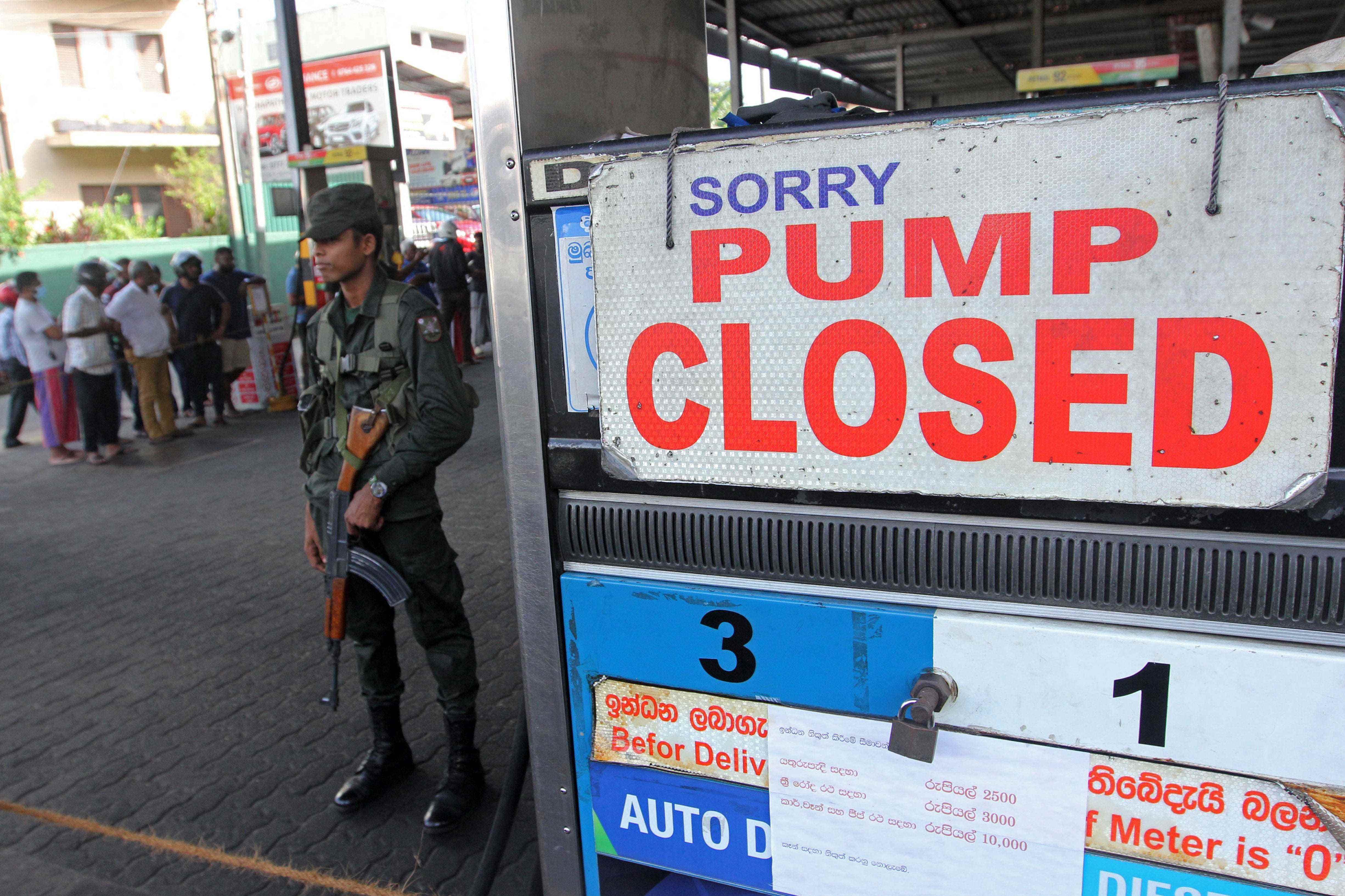Ein Mitglied des srilankischen Sicherheitspersonals steht am 27. Juni 2022 in Colombo vor einer Tankstelle, der das Benzin ausgegangen ist.