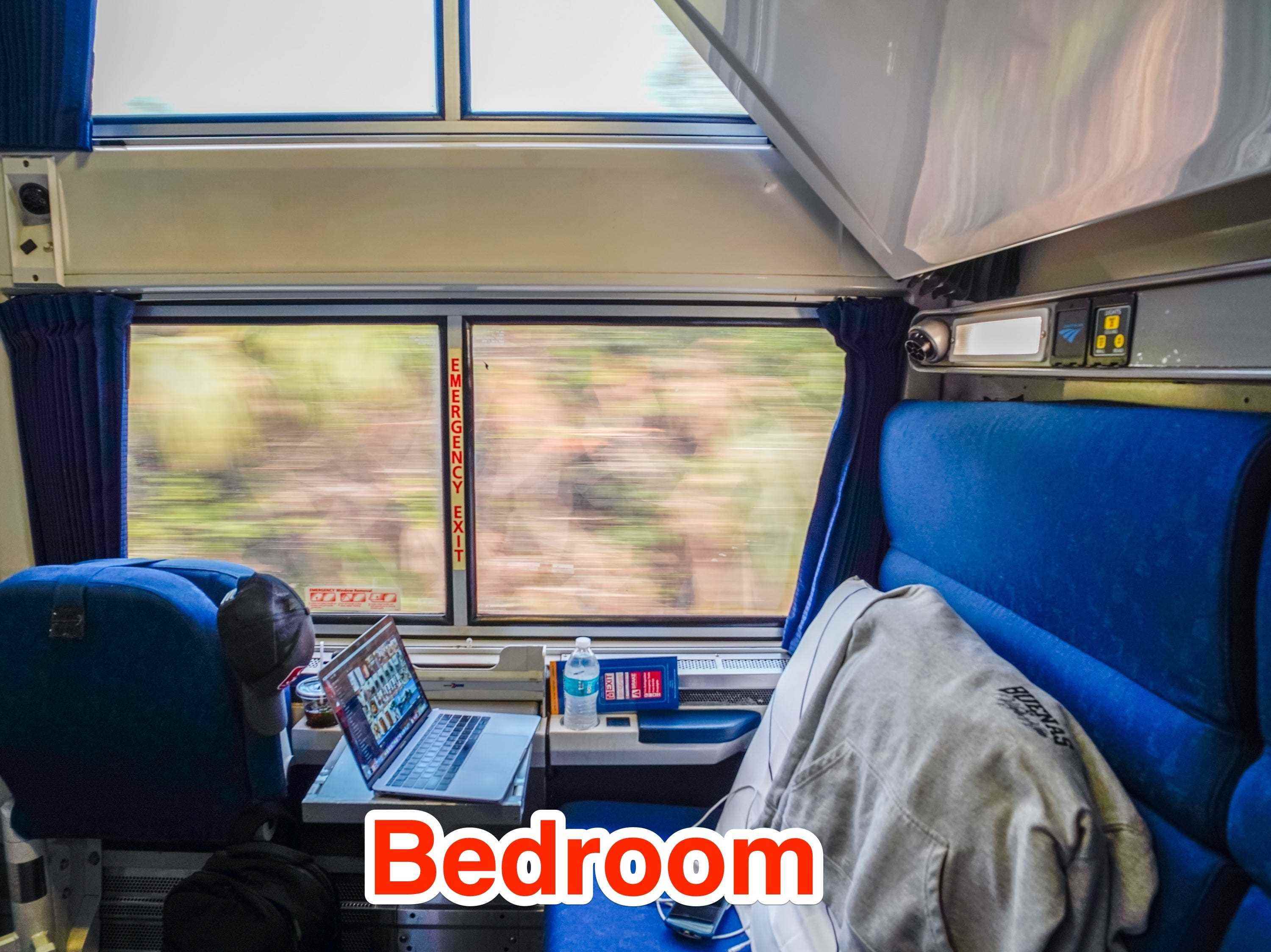 In einem Amtrak-Schlafzimmer mit blauen Sitzen und einem großen Fenster, das die Natur draußen zeigt