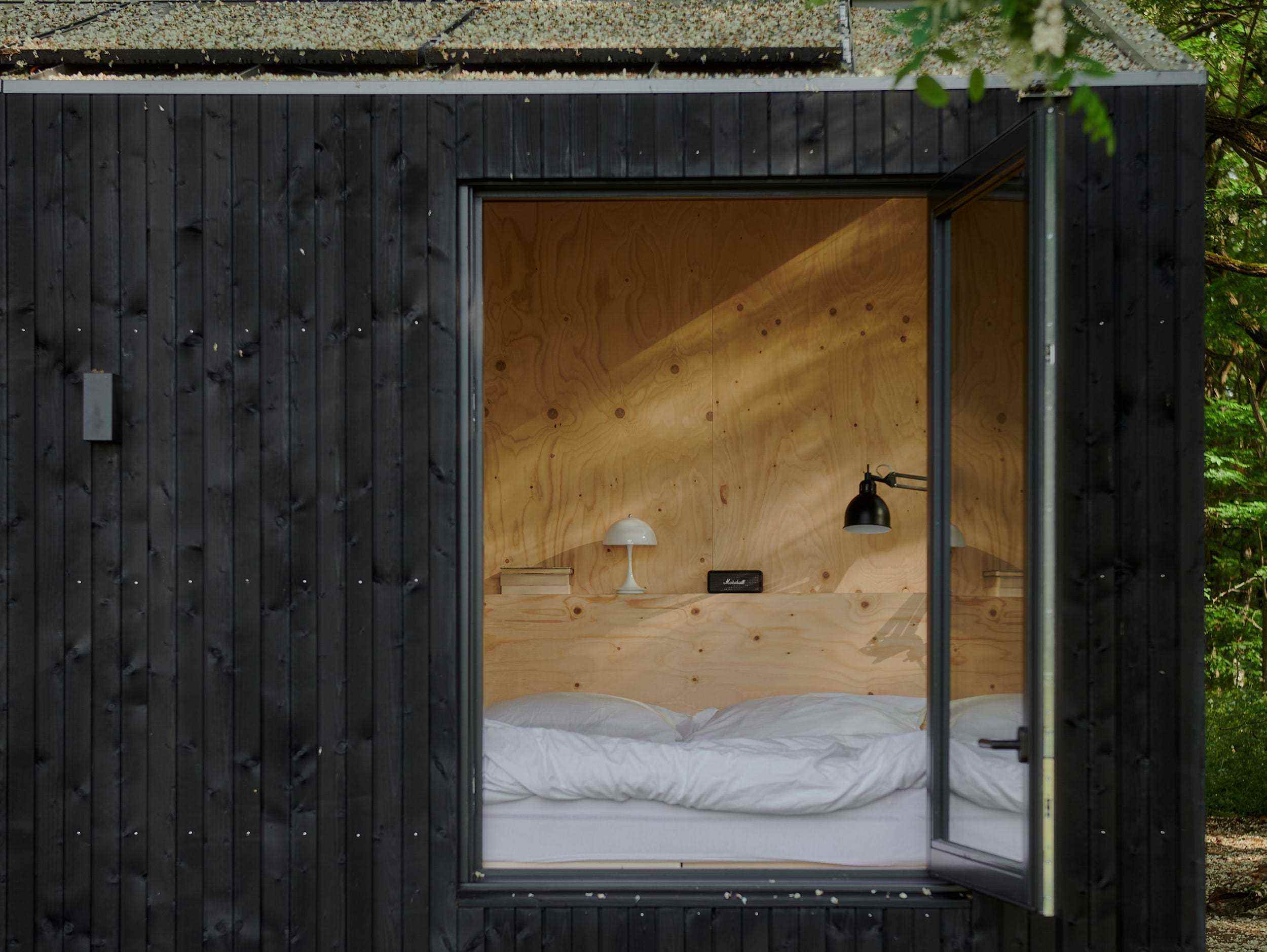 Ein Blick in eine Raus-Hütte mit einem Bett in der Nähe eines offenen Fensters.