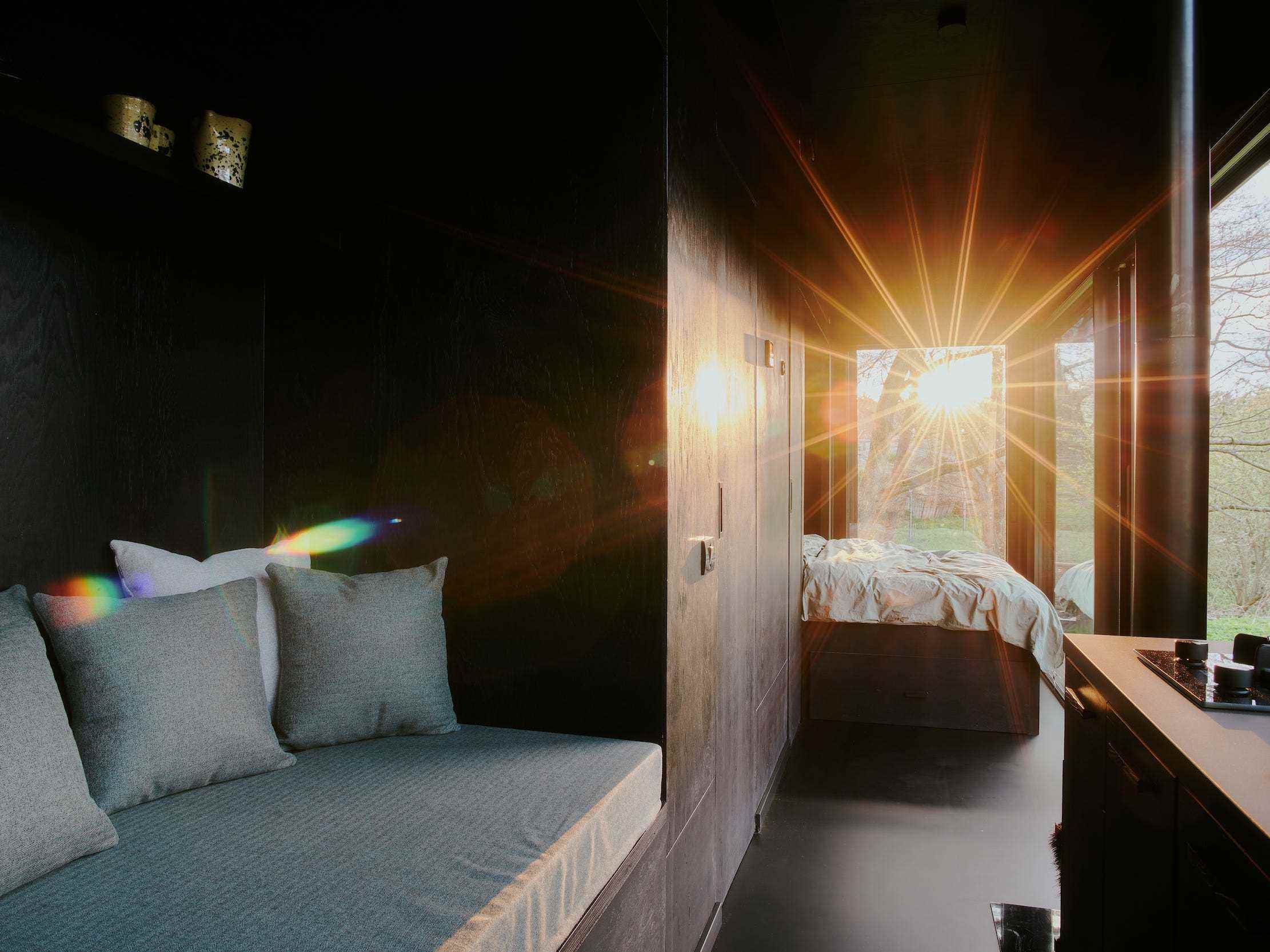 Sonne scheint durch das Fenster in einer Raus-Hütte mit Tagesbett, Bett.