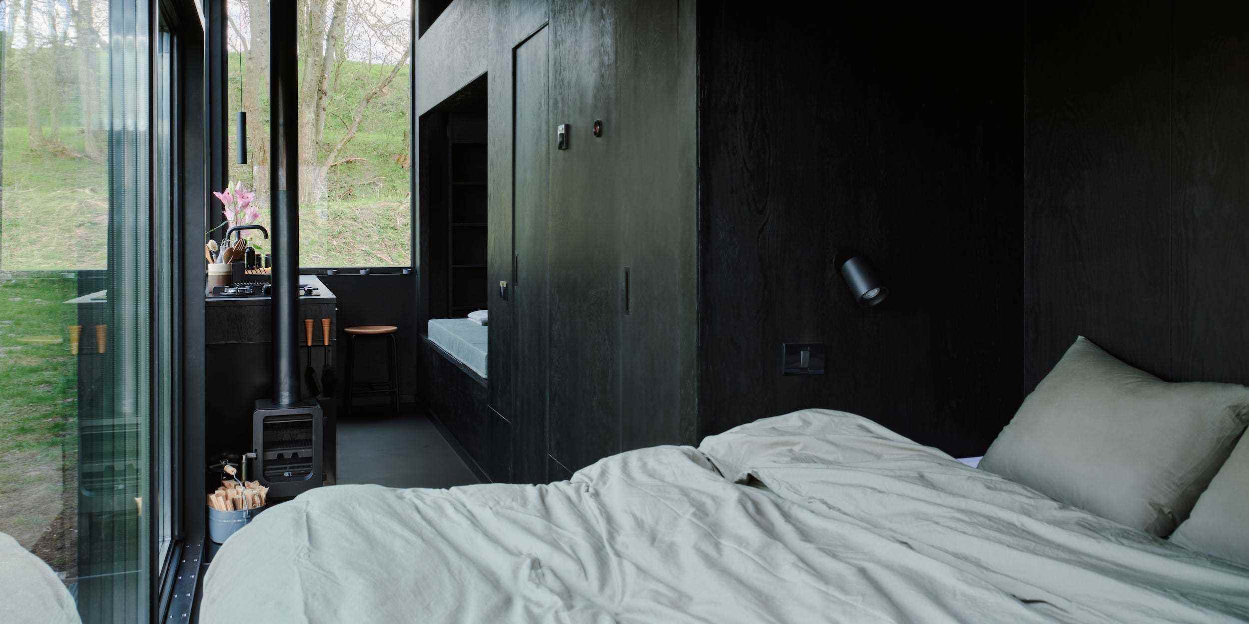 Ein Bett, eine Küche, ein Tagesbett mit Fenstern, die die Natur draußen zeigen