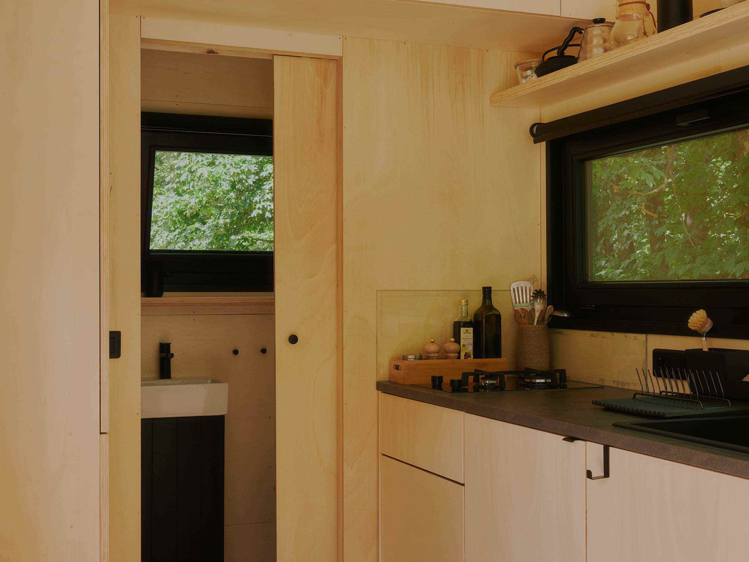 Ein Blick in eine Raus-Hütte mit Bad, Küche, Fenstern mit Blick in die Natur.