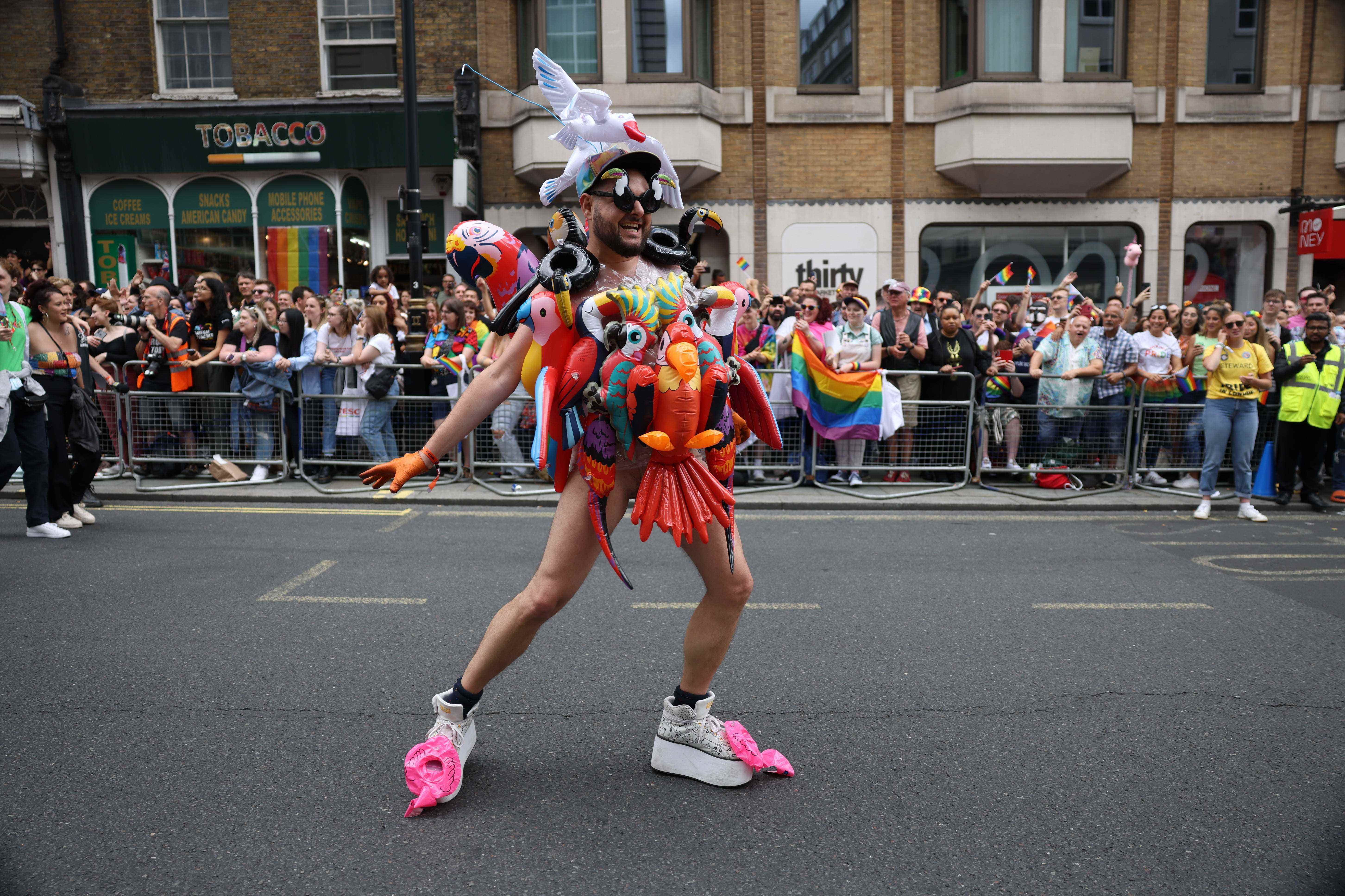 Ein Mann, der während der Pride in London mit aufblasbaren Papageien bedeckt ist.