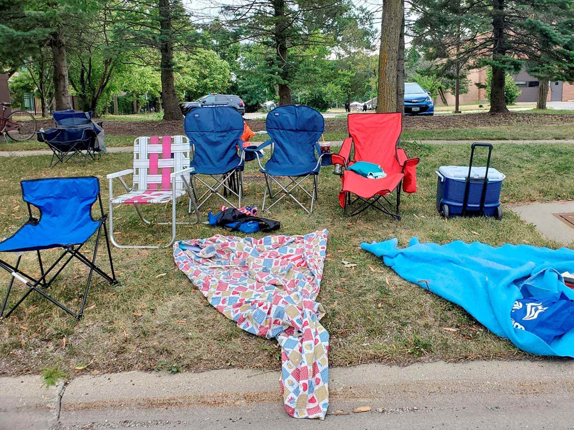 leere Liegestühle und Decken mit Kühler im Gras neben der Straße