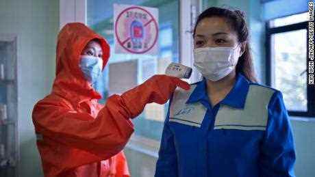 Ein Gesundheitspersonal der Kosmetikfabrik in Pjöngjang misst die Temperatur einer Frau, die am 16. Juni zu ihrer Schicht kommt.