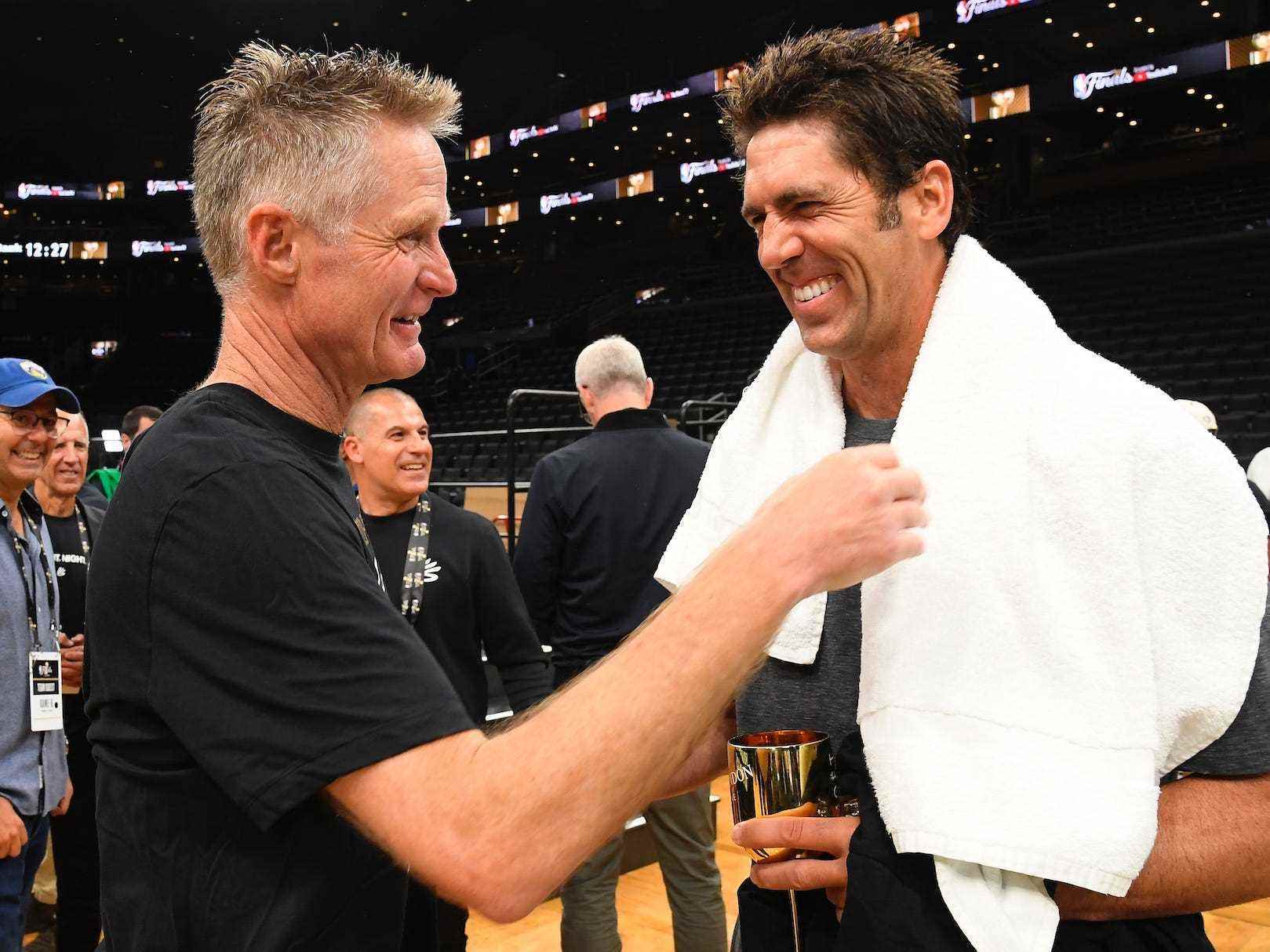 Steve Kerr und Bob Myers lächeln, während sie sich unterhalten, nachdem die Warriors die Meisterschaft 2022 gewonnen haben.