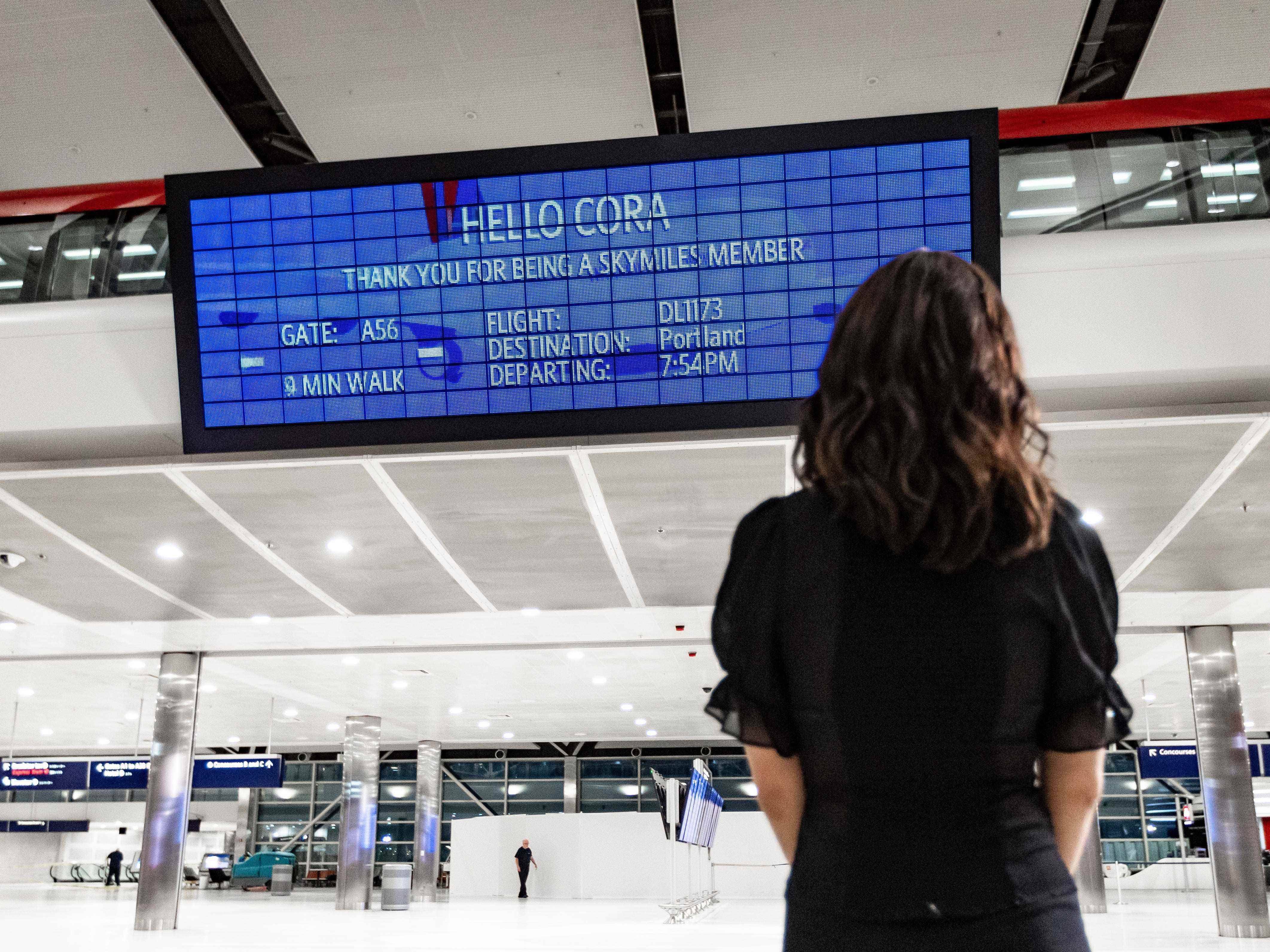 Eine Frau schaut auf das Parallel Reality Board im Flughafen von Detroit, das ihre Fluginformationen anzeigt.