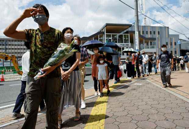 An dem Ort, an dem Shinzo Abe erschossen wurde, stehen Menschen Schlange, um Blumen anzubieten und zu beten