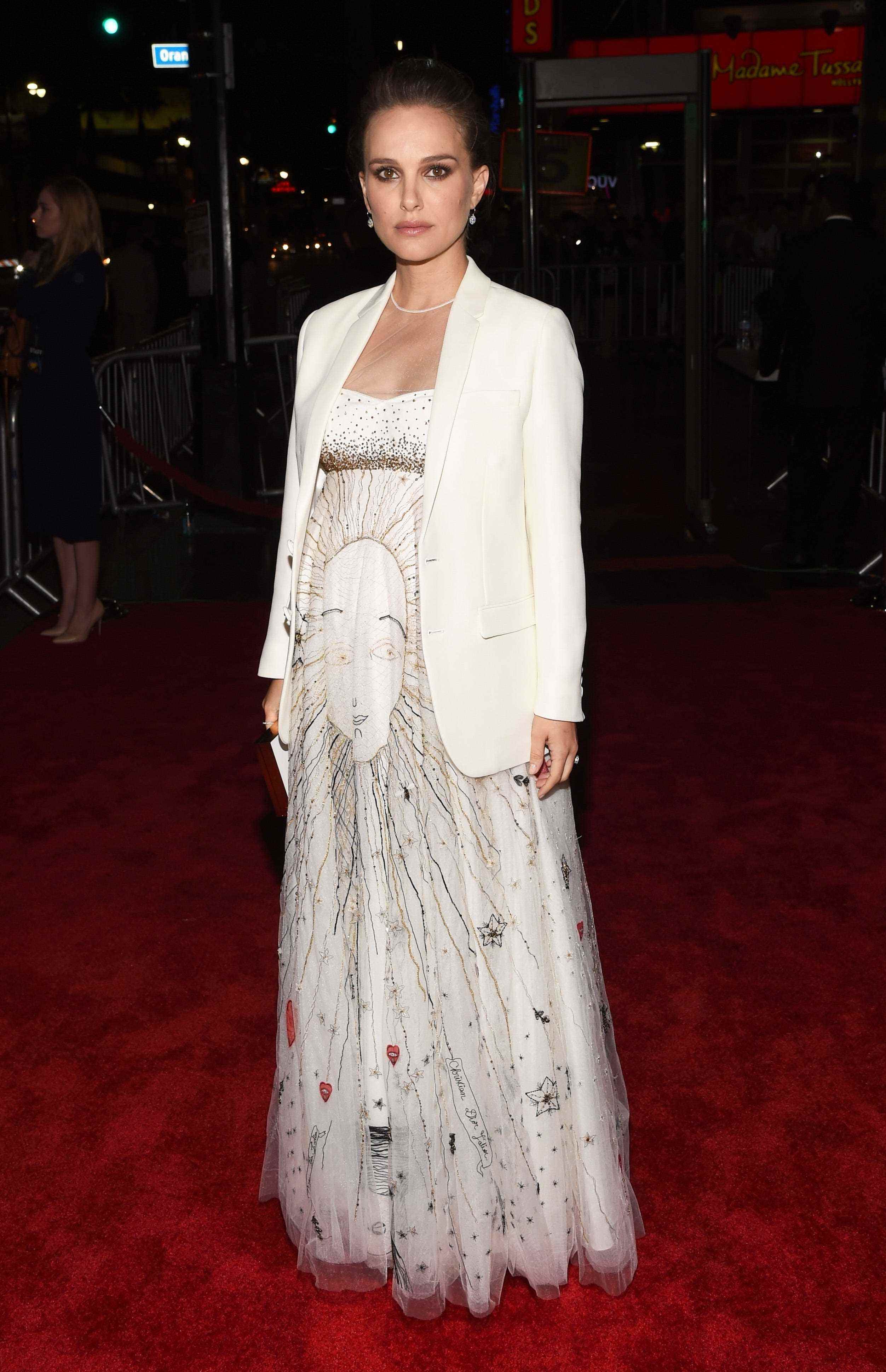 Natalie Portman in einem weißen Blazer und einem weißen Kleid auf einem roten Teppich