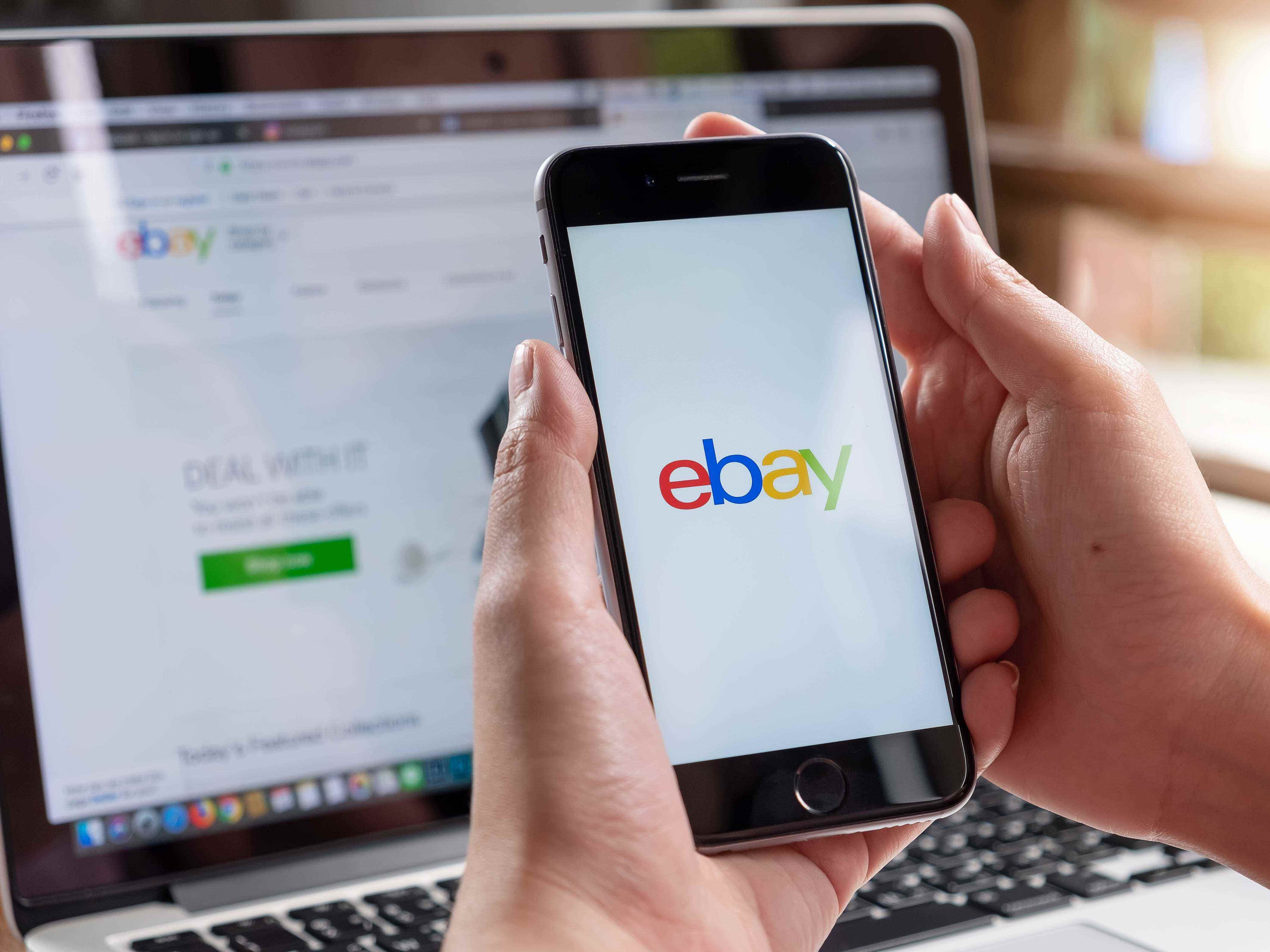 Eine Hand hält ein Telefon mit dem eBay-Logo auf dem Bildschirm.