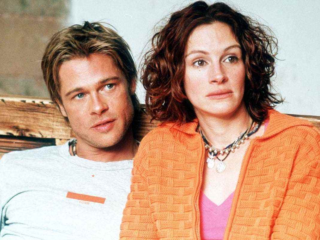 Jerry in einem weißen T-Shirt und Samantha in einem orangefarbenen Pullover und einem rosa Hemd sitzen in diesem Standbild aus dem Film „The Mexican“ von 2001 auf einer Couch.