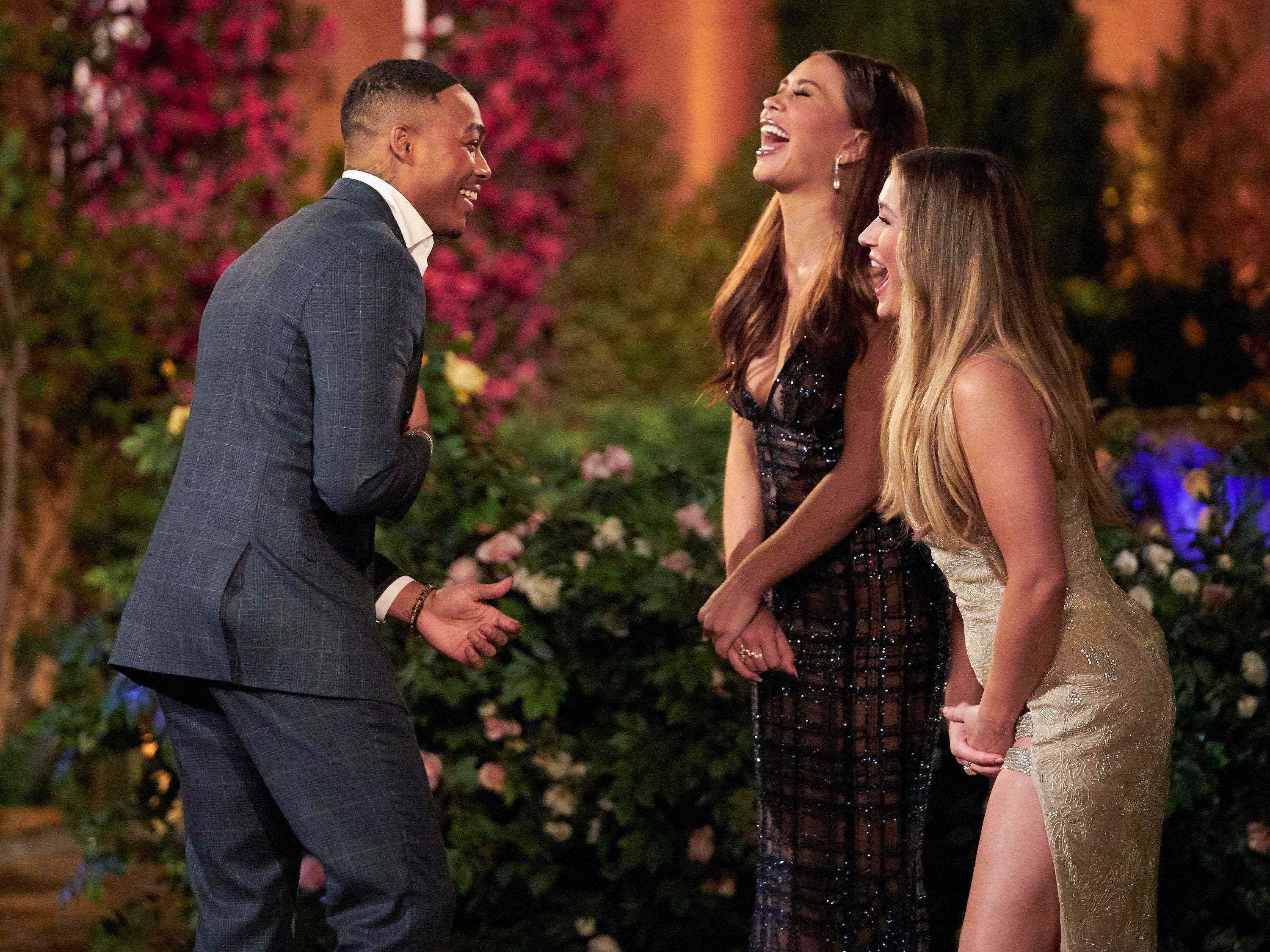 Quincy, in einem dunklen Anzug, lacht mit Gabby Windey und Rachel Recchia vor der Villa in diesem Standbild aus der Premiere der 19. Staffel von „The Bachelorette“.