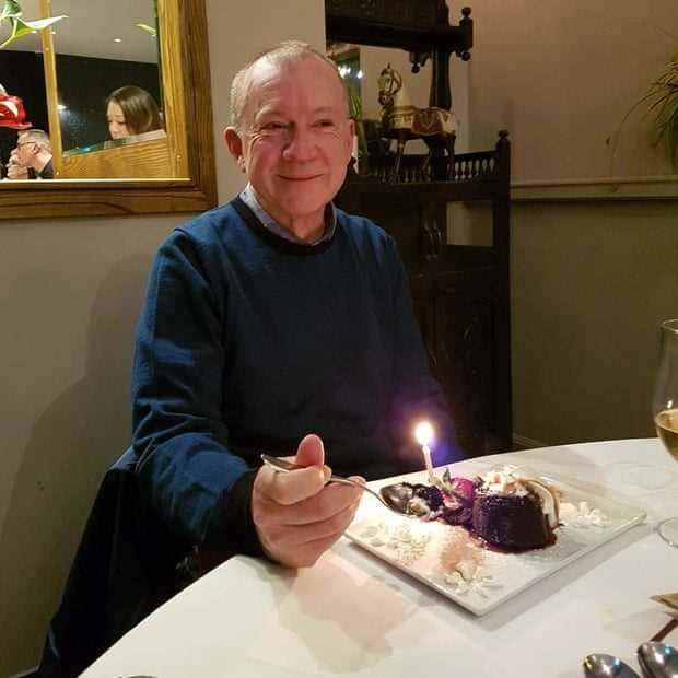 Des, ein älterer Mann, sitzt lächelnd vor einem Kuchen mit Kerze