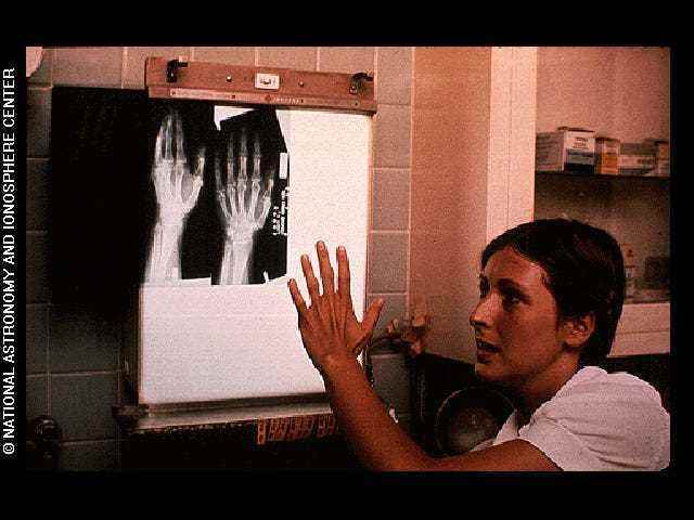 Dieses Bild zeigt eine Frau, die sich ein Röntgenbild ihrer eigenen Hand ansieht.  Es wurde in die Goldene Schallplatte aufgenommen.