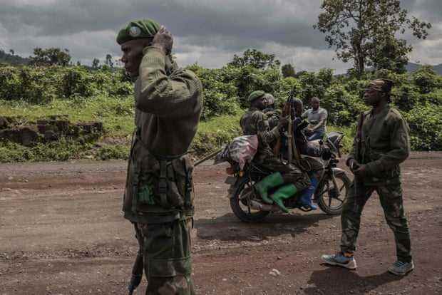 Ein Motorrad mit zwei Soldaten überholt andere auf einer unbefestigten Straße