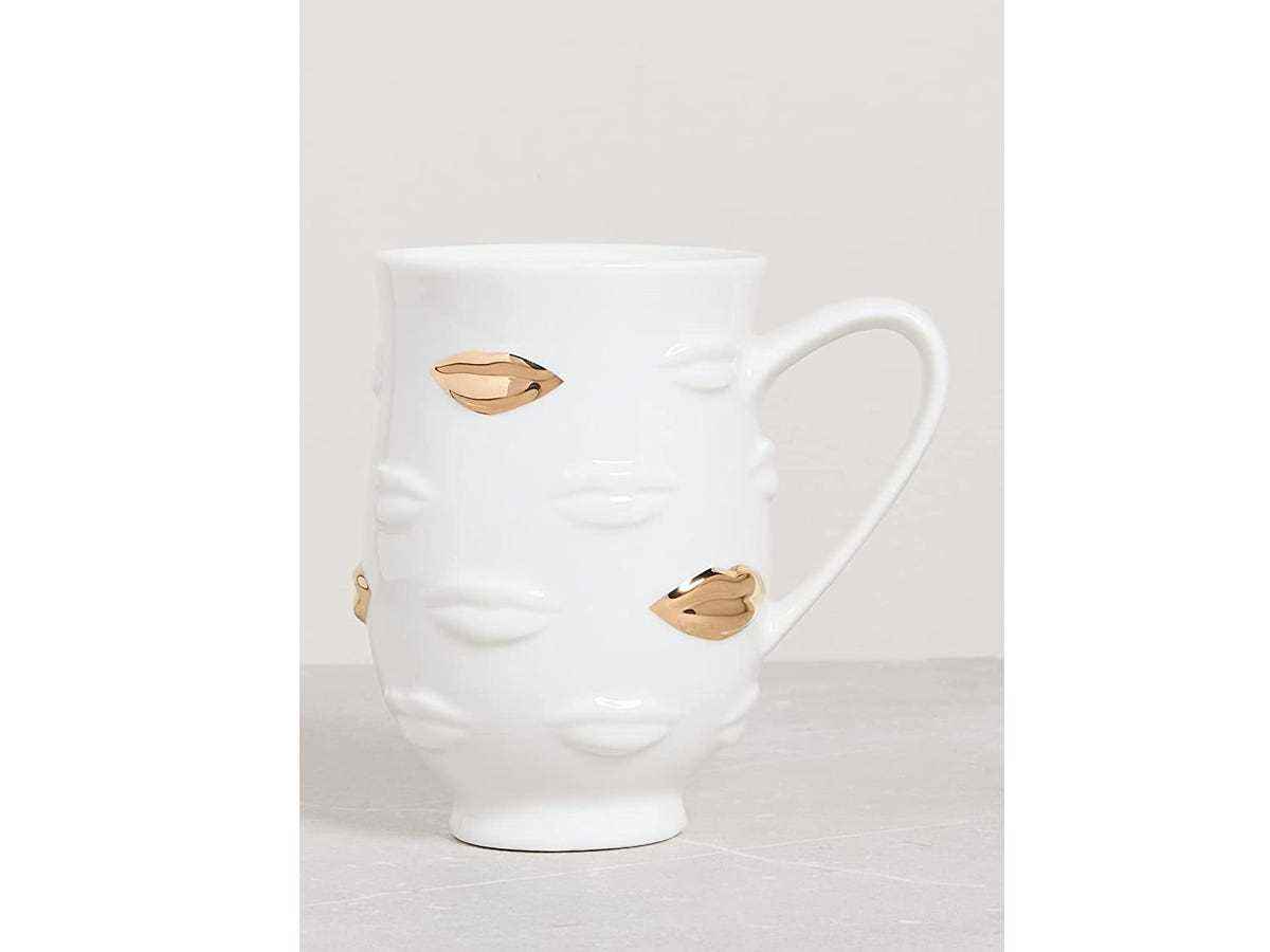 Eine weiße Tasse mit goldenen Lippen drauf.