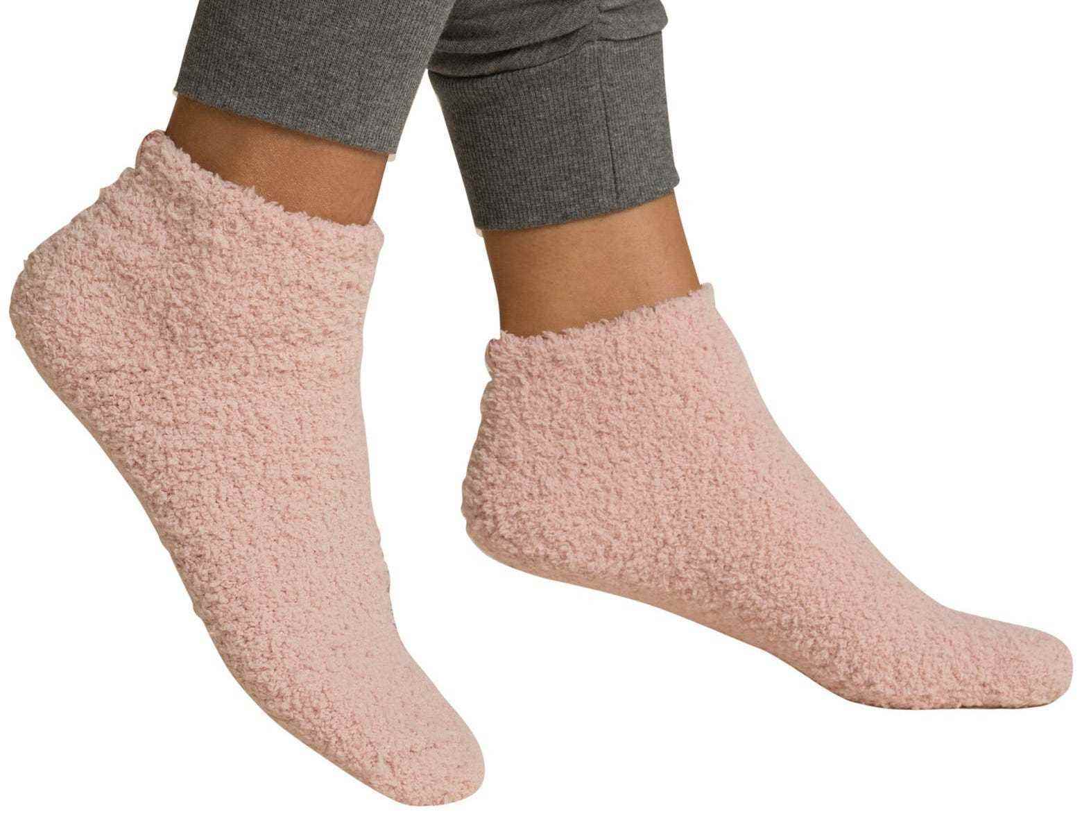 Eine Person, die ein Paar rosa Fuzzy-Socken trägt.