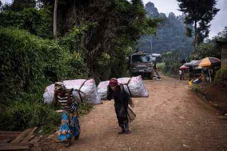Frauen tragen Säcke mit Holzkohle in einem Dorf in der Nähe des Nationalparks Kahuzi-Biega