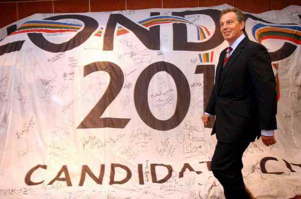 Der damalige britische Premierminister Tony Blair geht an einem großen London 2012-Banner vorbei, als er im Juli 2005 eine Pressekonferenz in einem Hotel in Singapur betritt