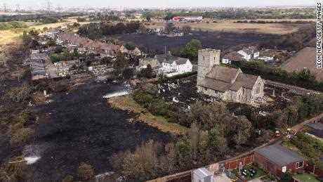 Der verbrannte Friedhof um eine Kirche nach einem großen Brand in Wennington im Osten Londons am Dienstag.  Großbritannien erlebte diese Woche eine rekordverdächtige Hitzewelle.  