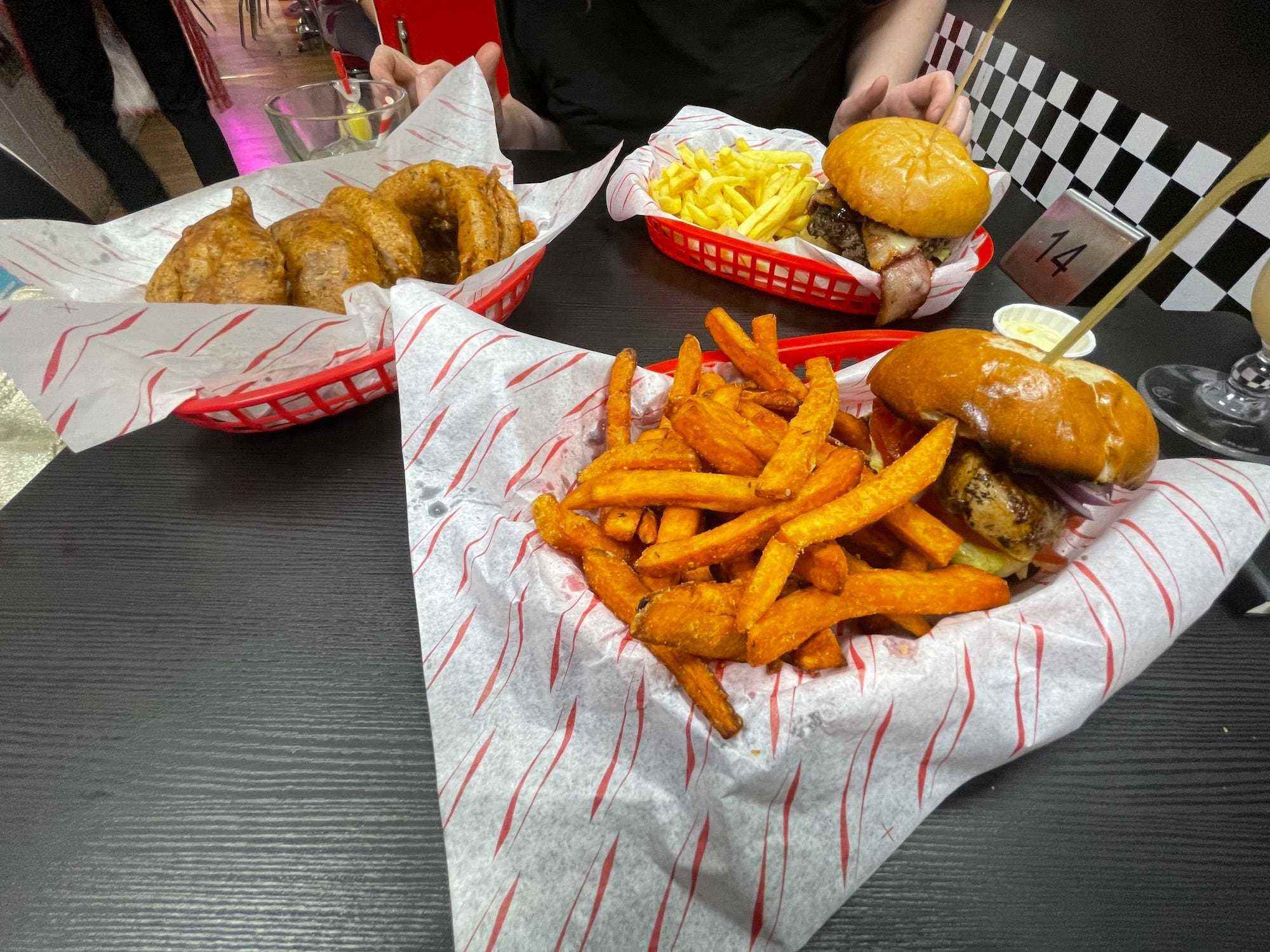 Zwei Burger und eine Portion Zwiebelringe bei Karen's Diner, serviert in Plastikschalen