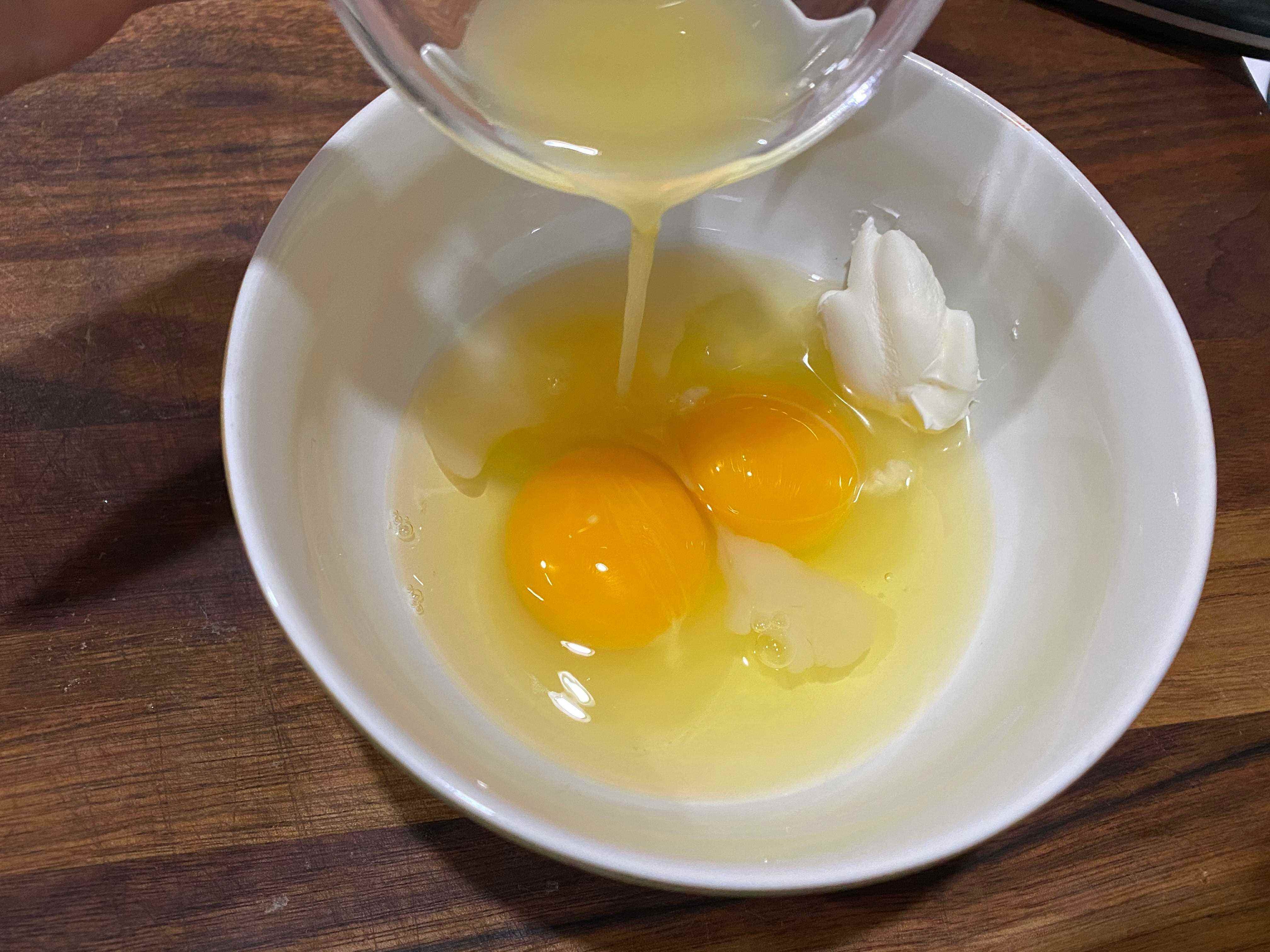 Orangensaft in eine Schüssel mit zwei aufgeschlagenen Eiern gießen