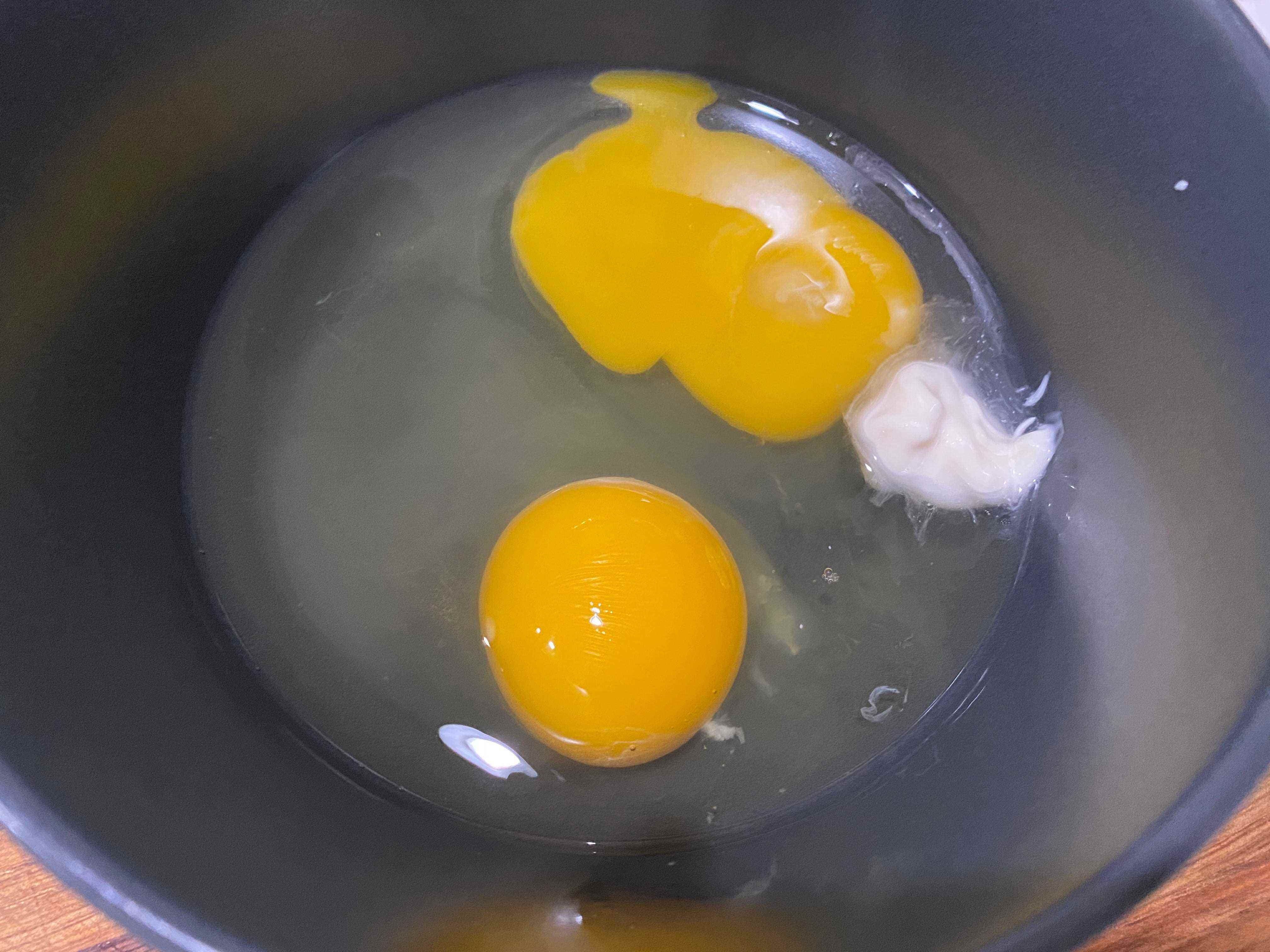 Mayonaise in einem Bogen mit zwei aufgeschlagenen Eiern