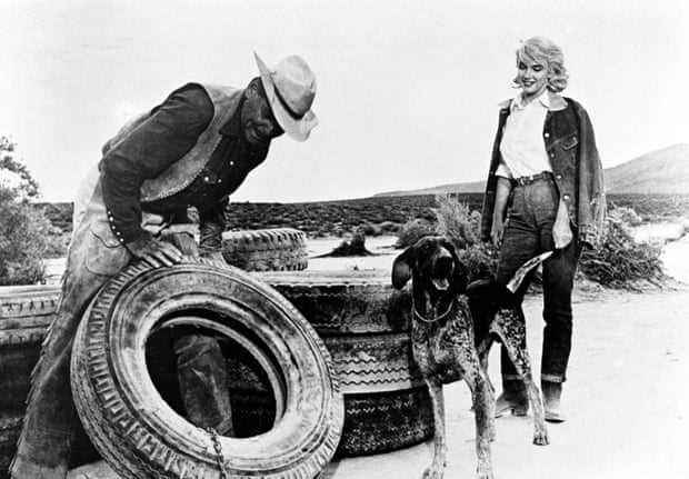 Clark Gable repariert einen Traktorreifen, während Monroe in The Misfits zuschaut.