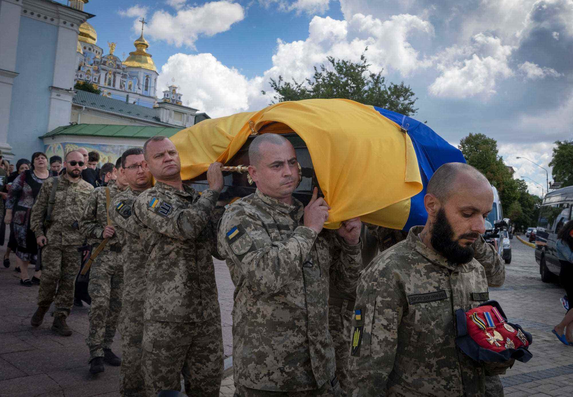 Ukrainische Soldaten in Tarnkleidung tragen einen Sarg, der in eine ukrainische Flagge gehüllt ist