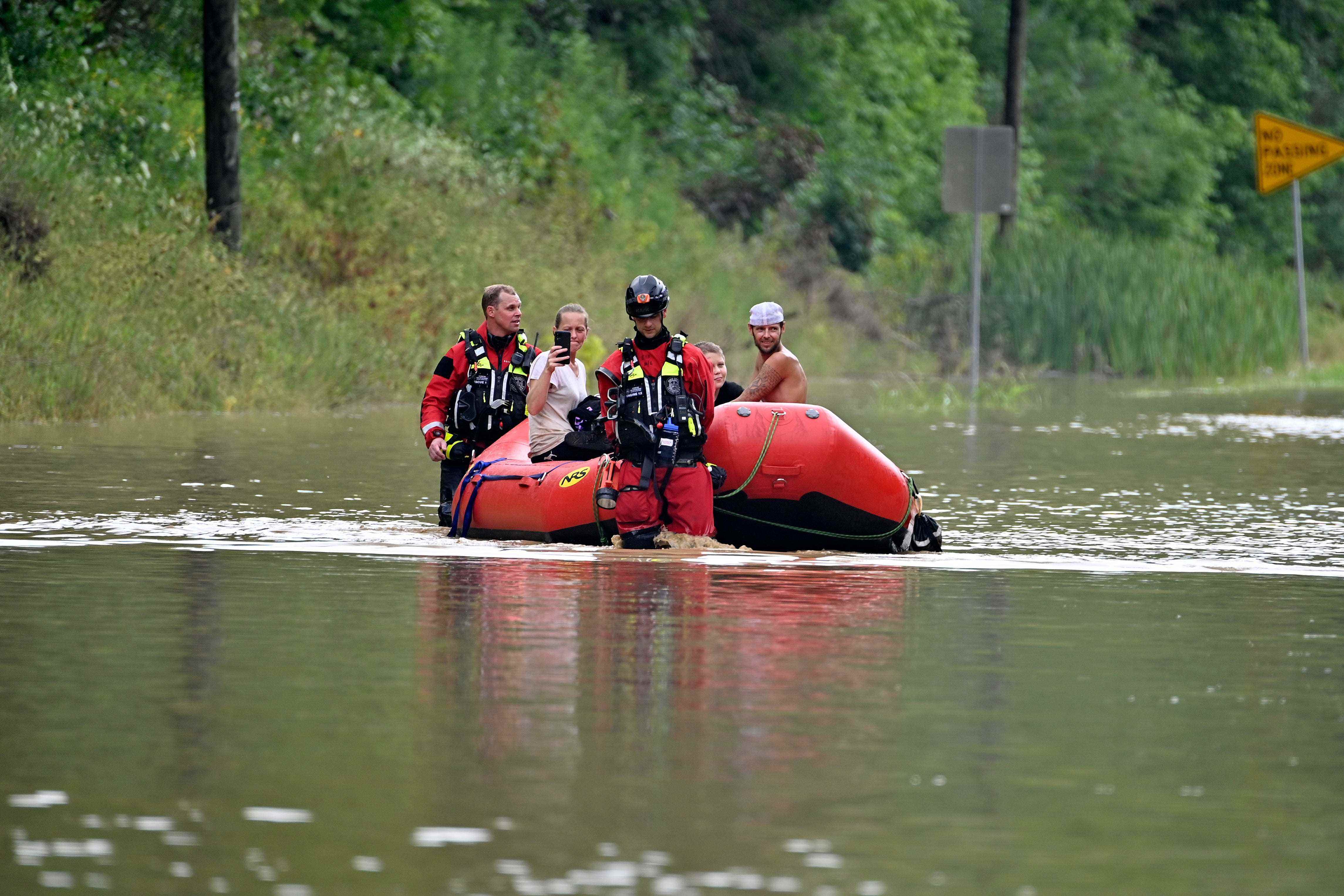 Rettungskräfte führen ein Schlauchboot mit einer Frau im Inneren über das Hochwasser.