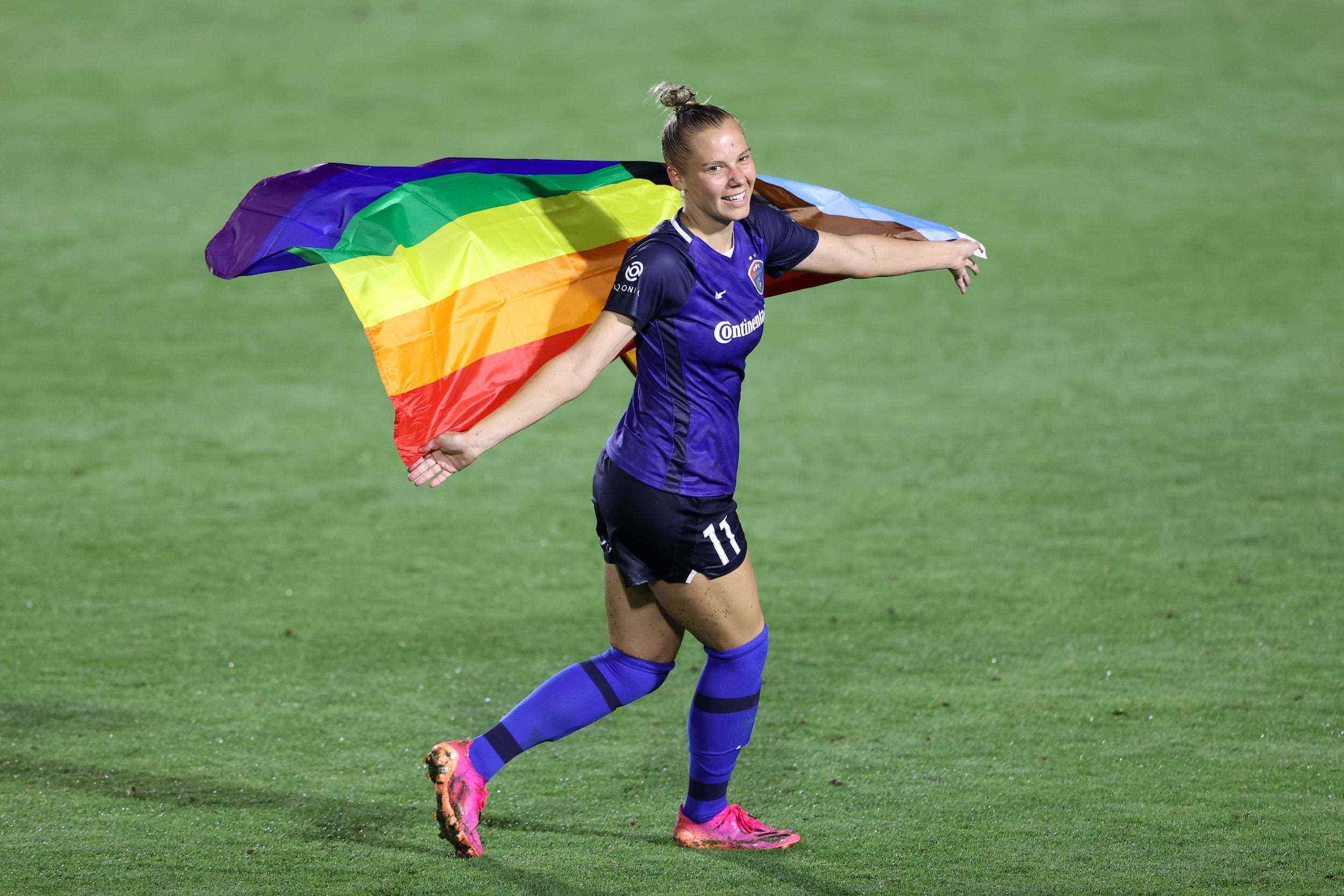 Mutiger Stürmer Merritt Mathias posiert mit einer Regenbogen-Pride-Flagge nach einem Spiel gegen die Portland Thorns in der Pride-Nacht 2021 in North Carolina.