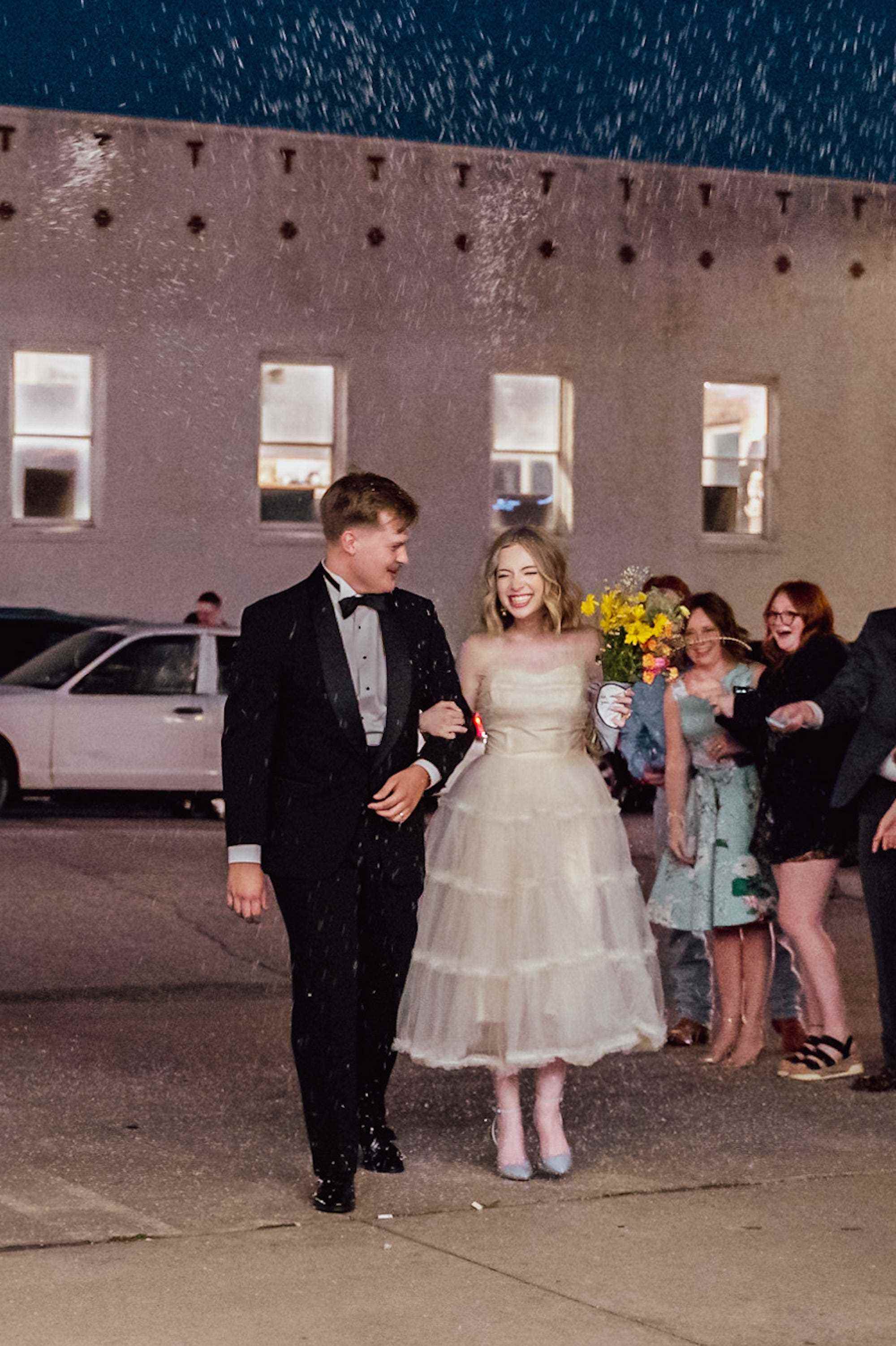 Ein Brautpaar grinst und verlässt gemeinsam ihren Hochzeitsempfang.